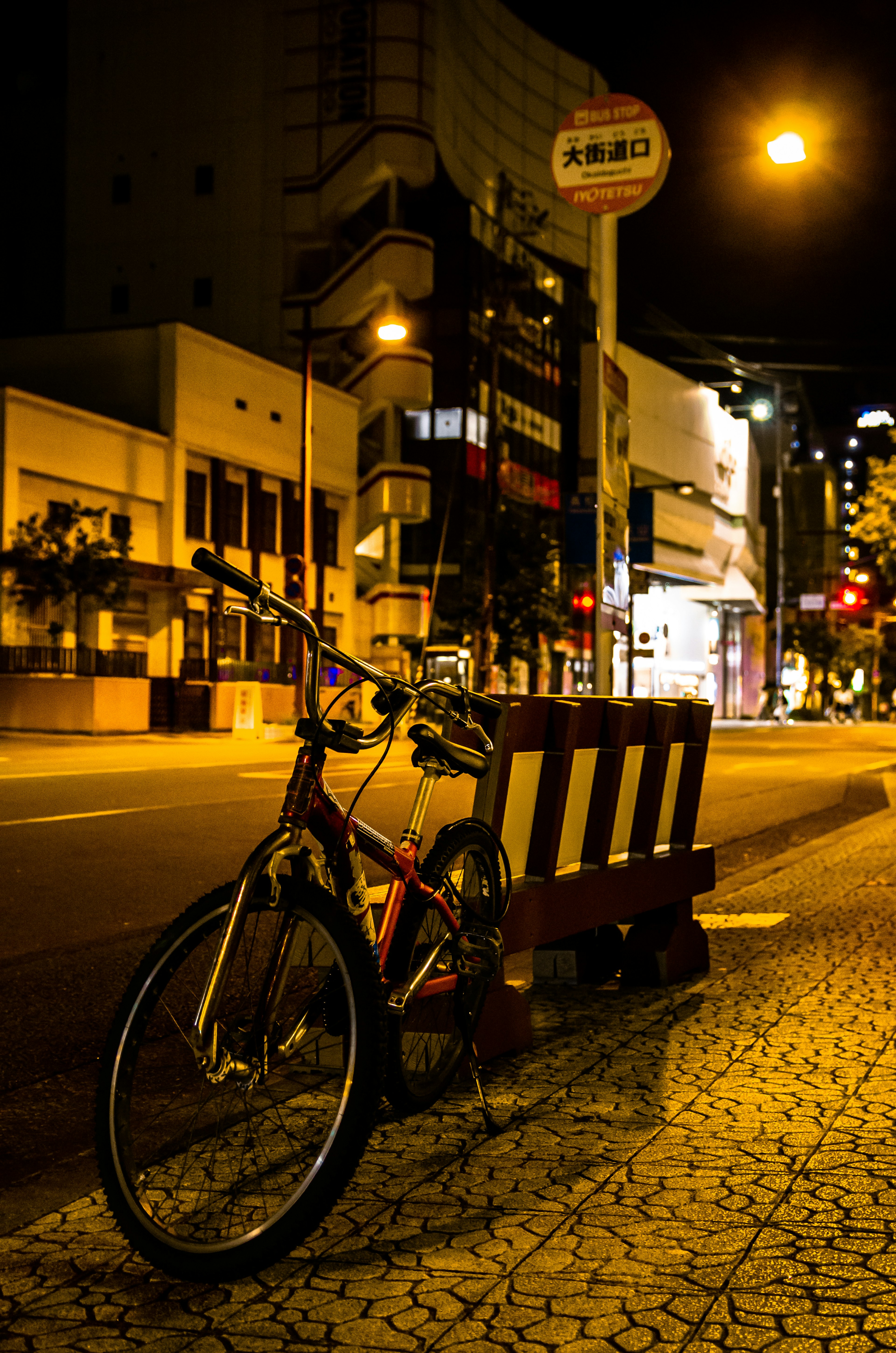 Bicycle parked on a quiet street at night with streetlights