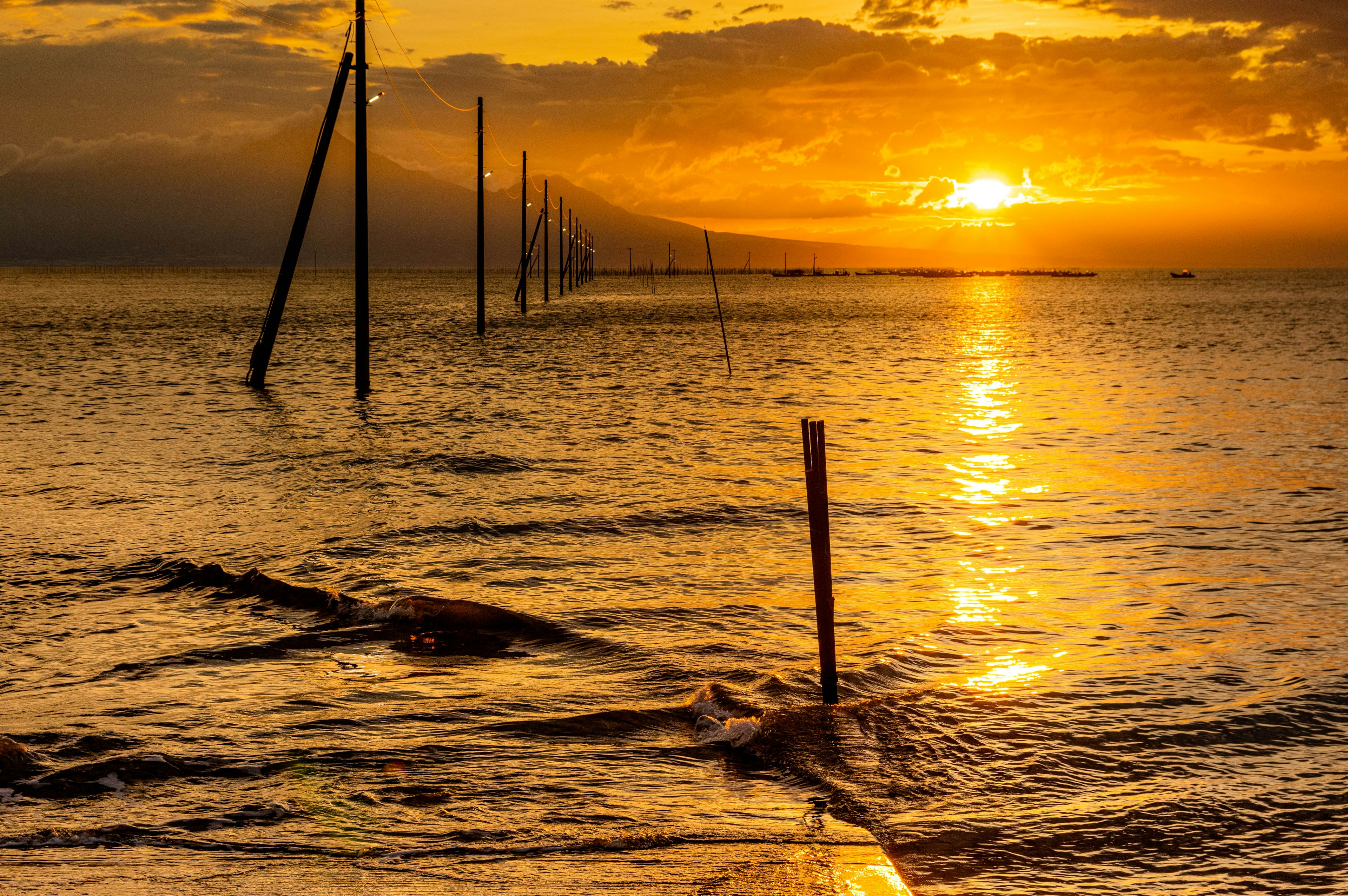 Bellissimo tramonto sul mare con riflessi arancioni sull'acqua e lunghi pali