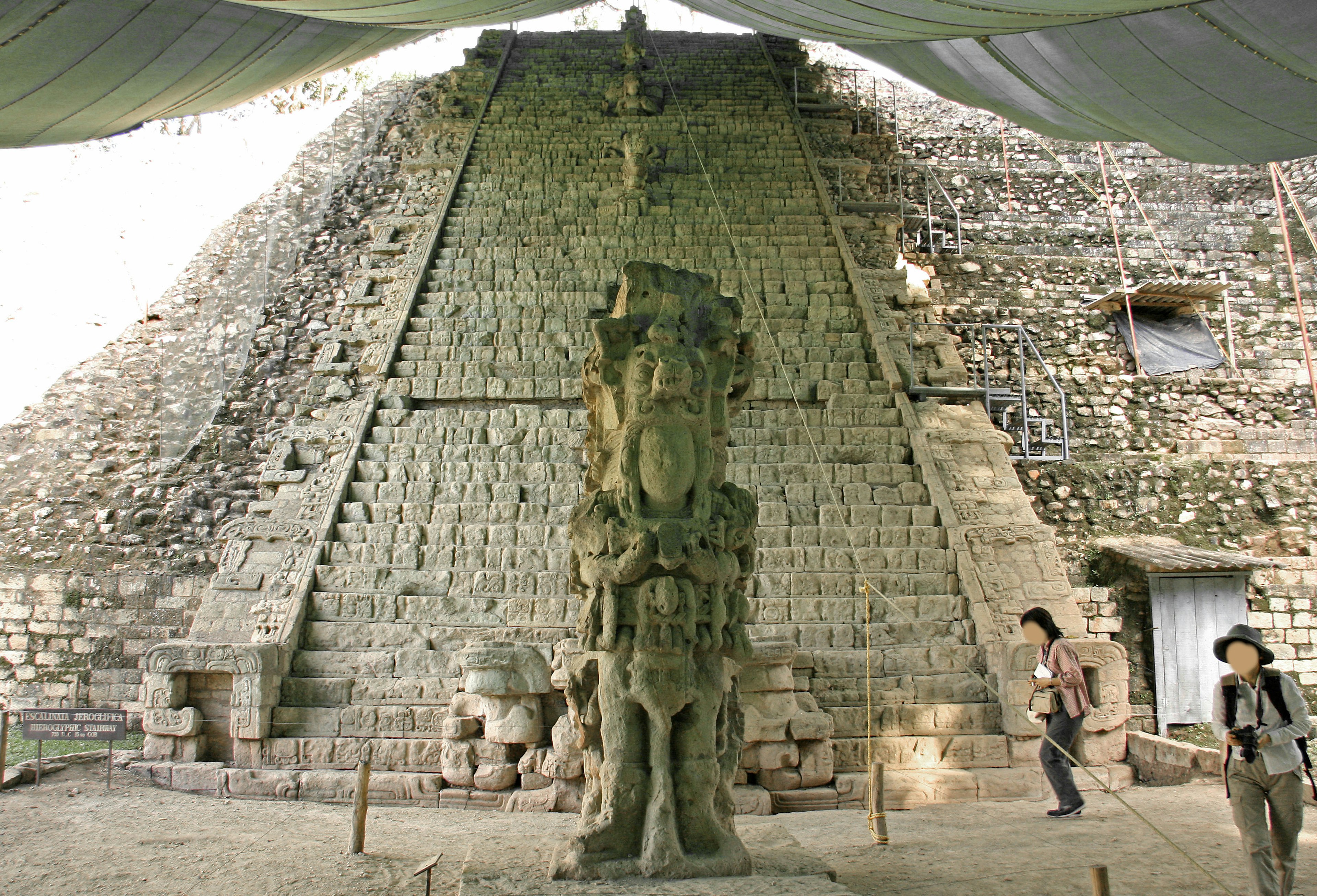 Ruinas antiguas con una pirámide de piedra y una estatua tallada