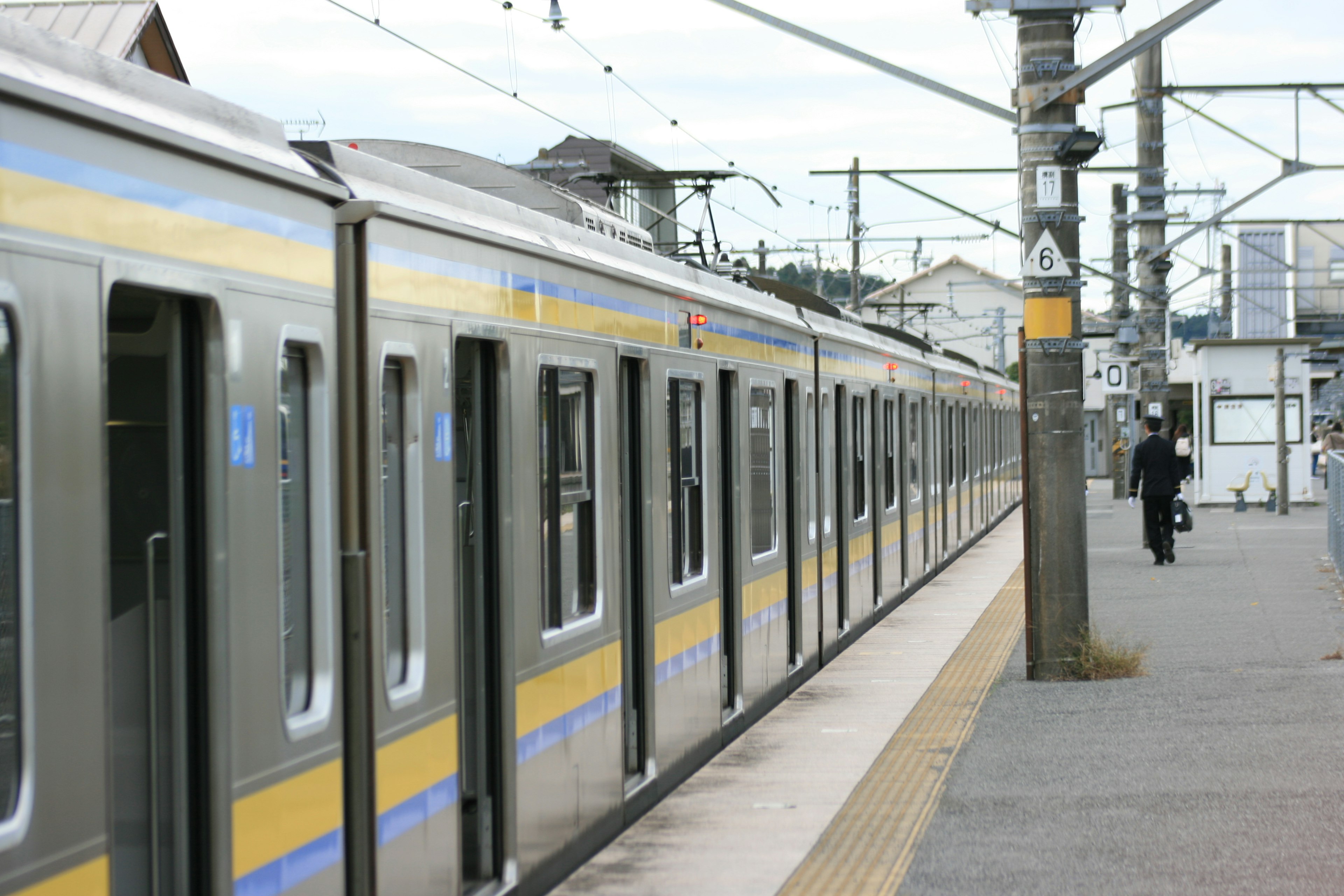 A train at a station with silver cars featuring blue and yellow stripes