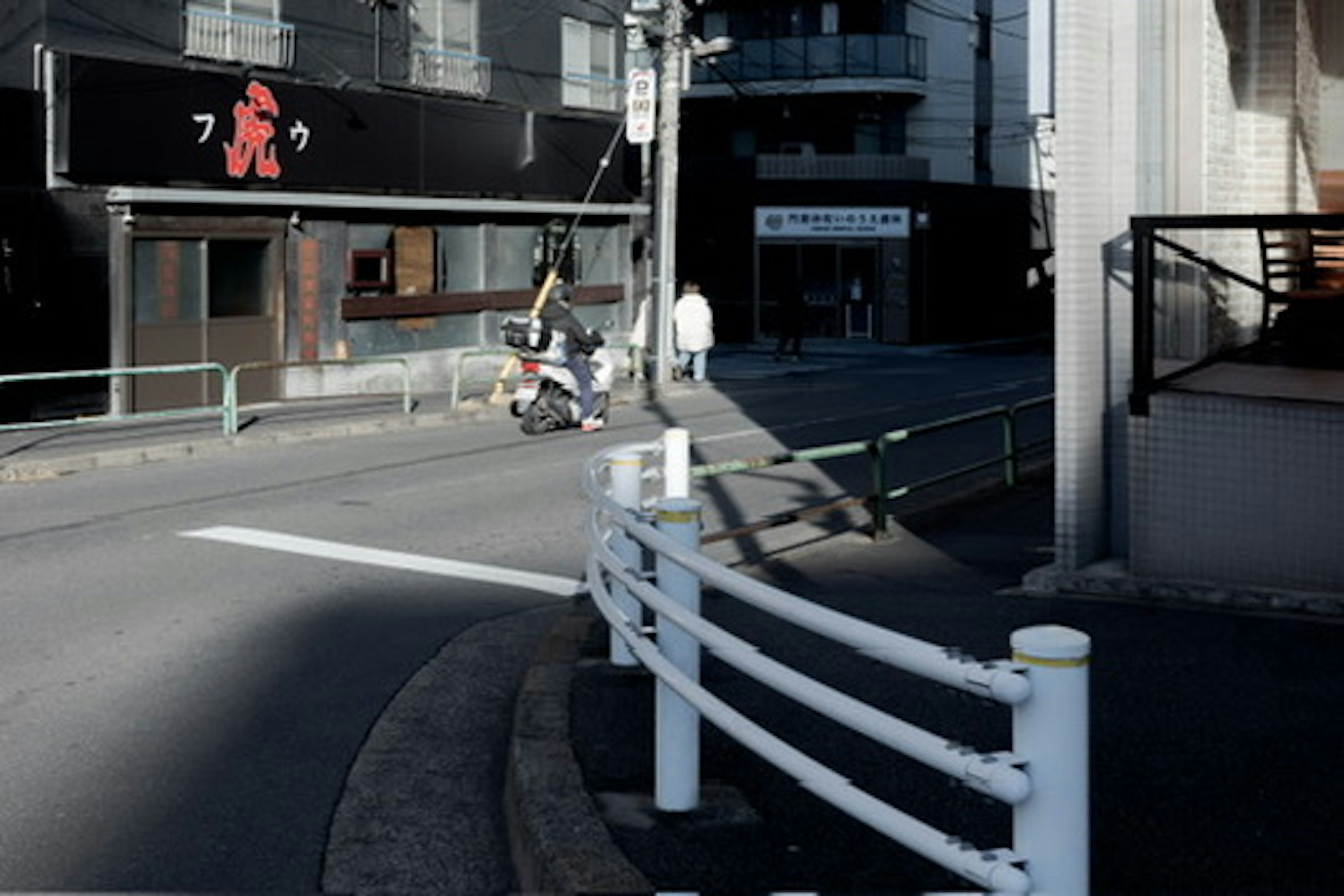 街角の風景にある白い手すりと店舗の外観