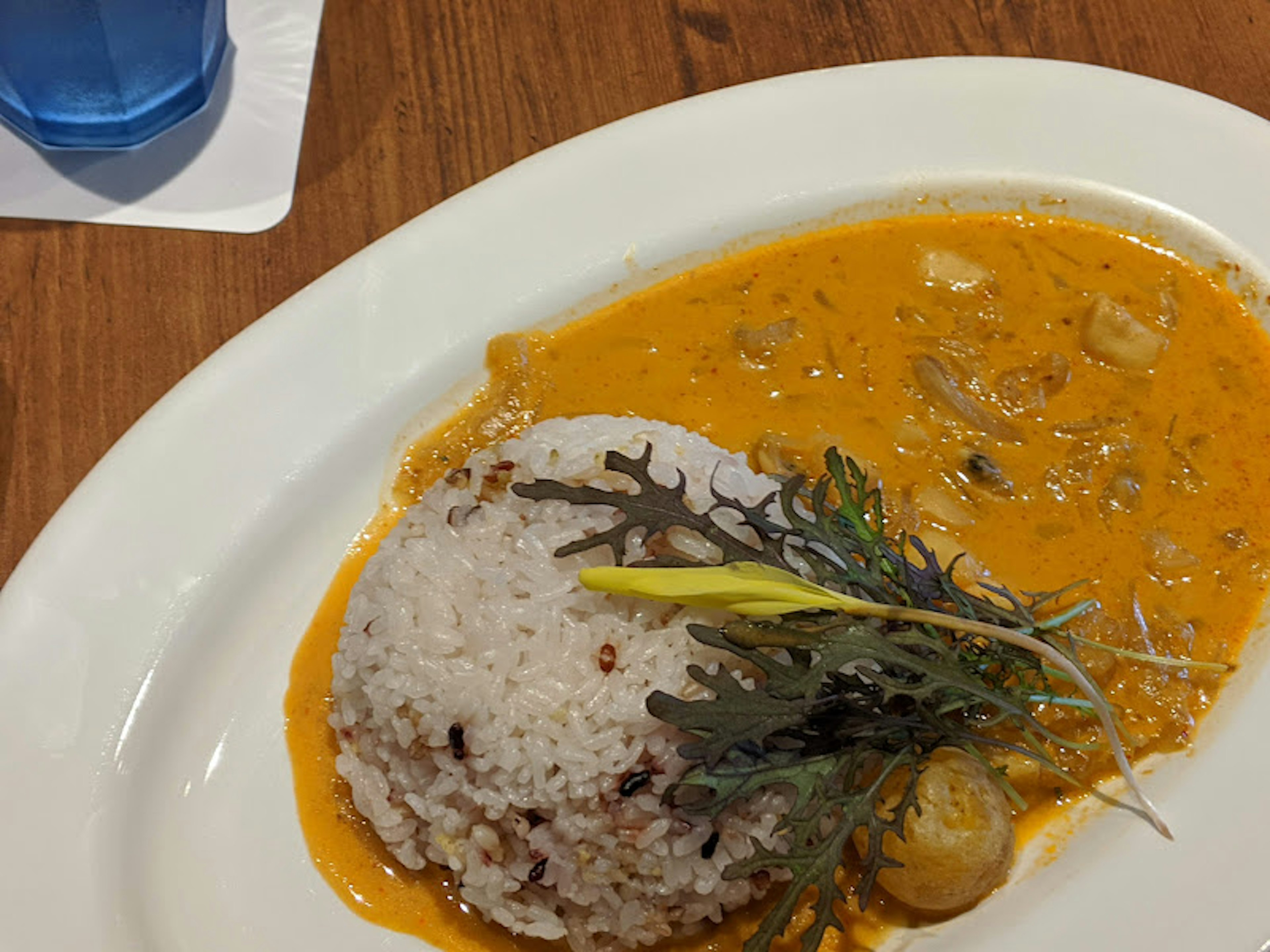 Gericht mit weißem Reis und orangefarbener Currysauce garniert mit Kräutern