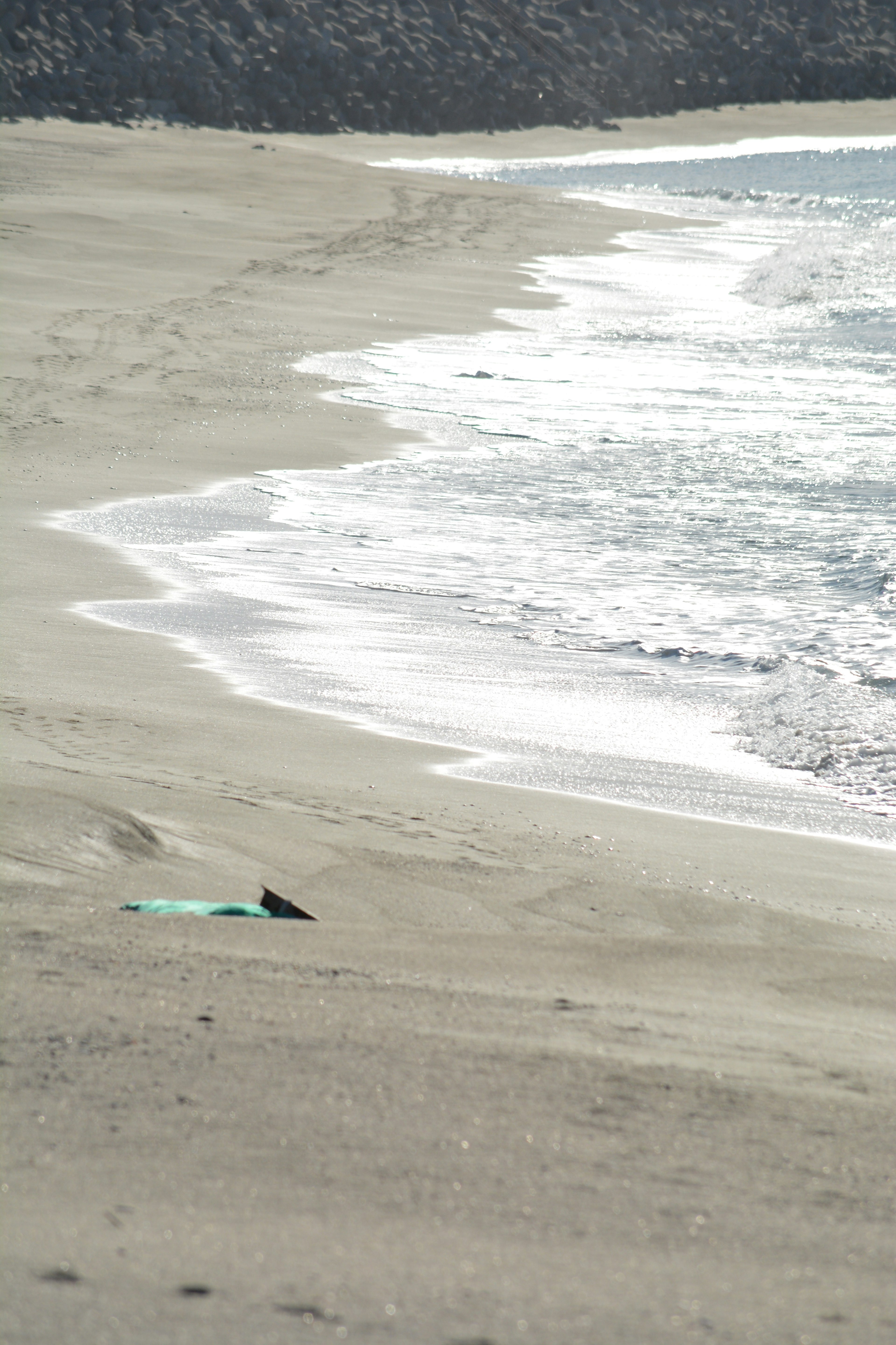 A tranquil beach with a surfboard lying on the sand and gentle waves