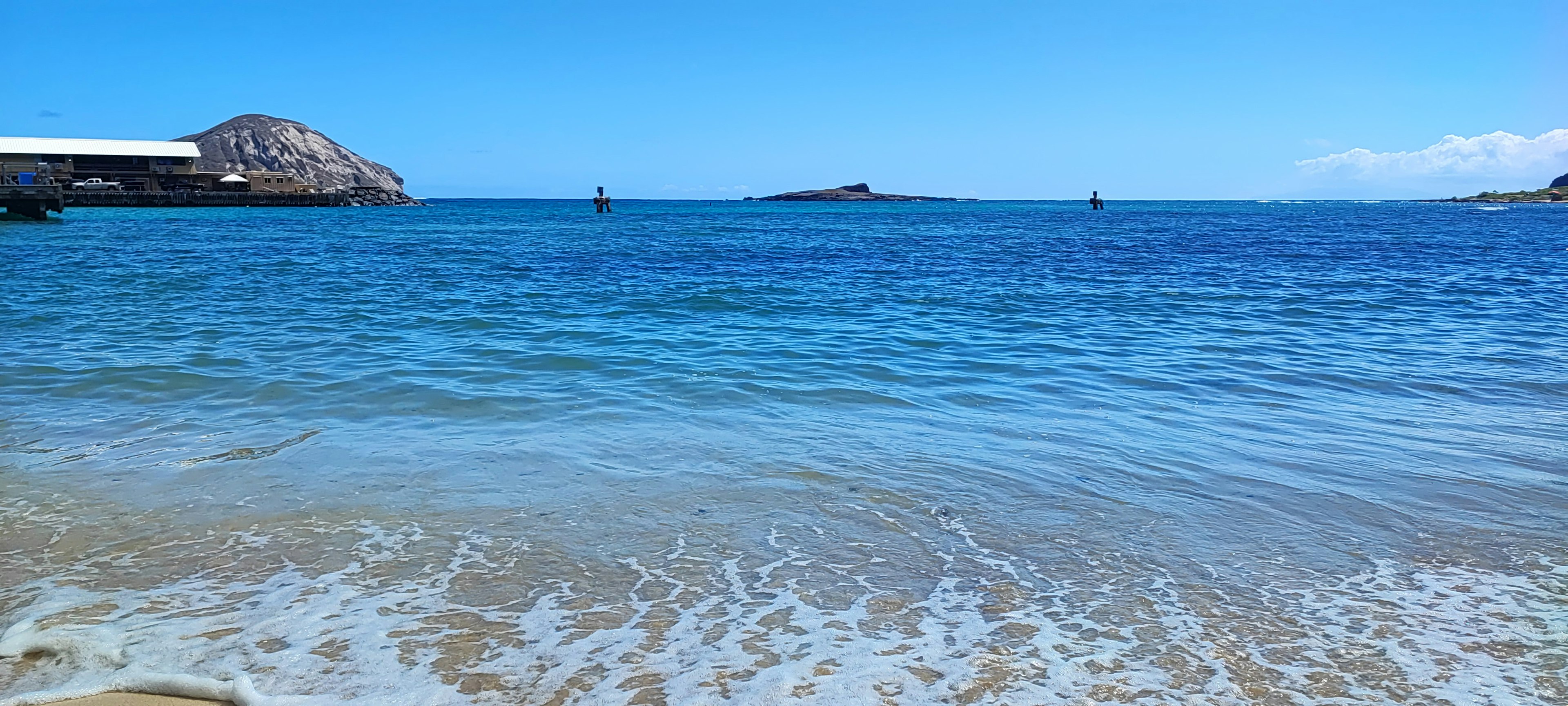 Pemandangan indah pantai tenang dengan air biru dan gelombang lembut