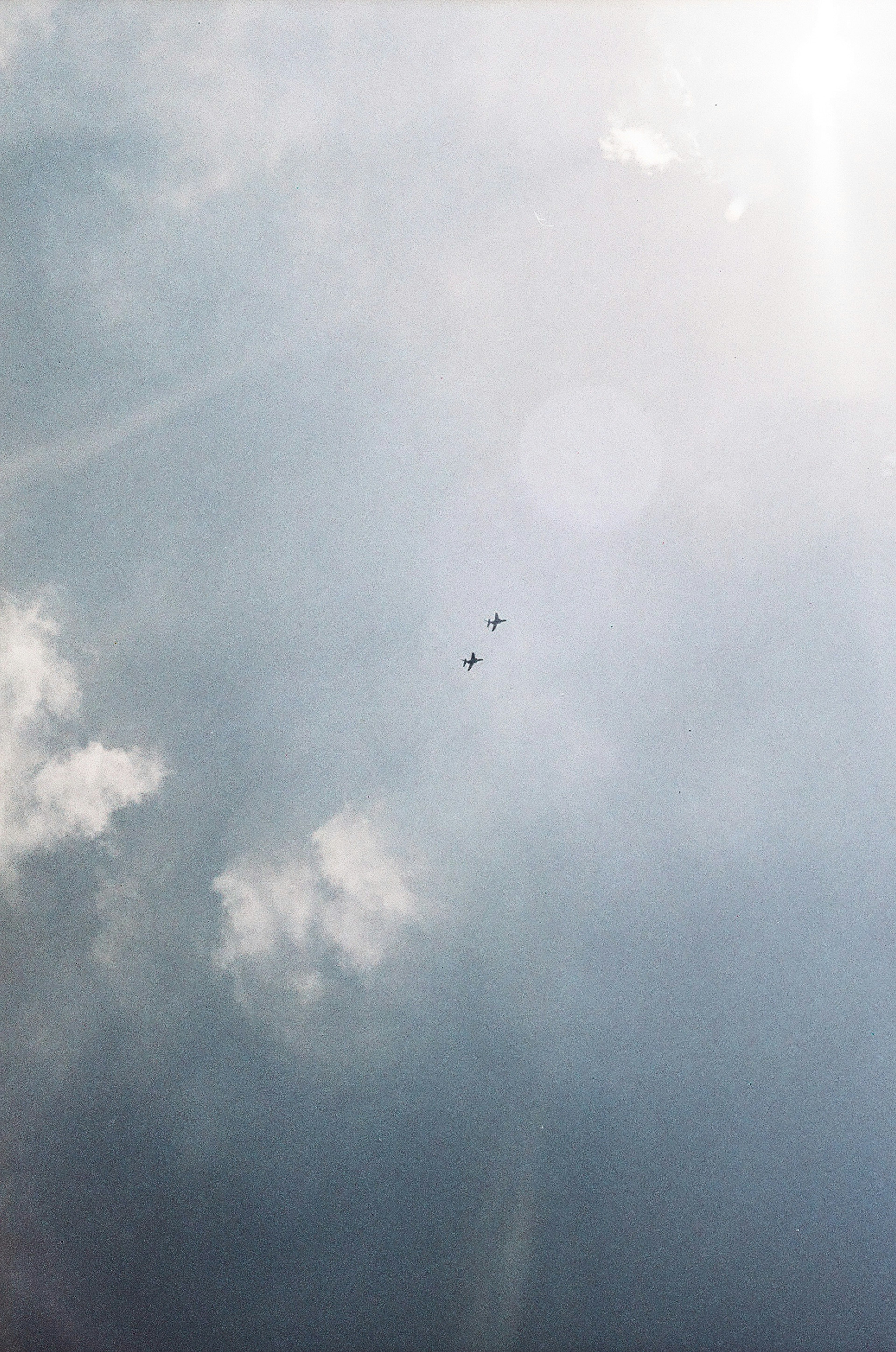 Two parachutes floating in the sky with a cloudy backdrop