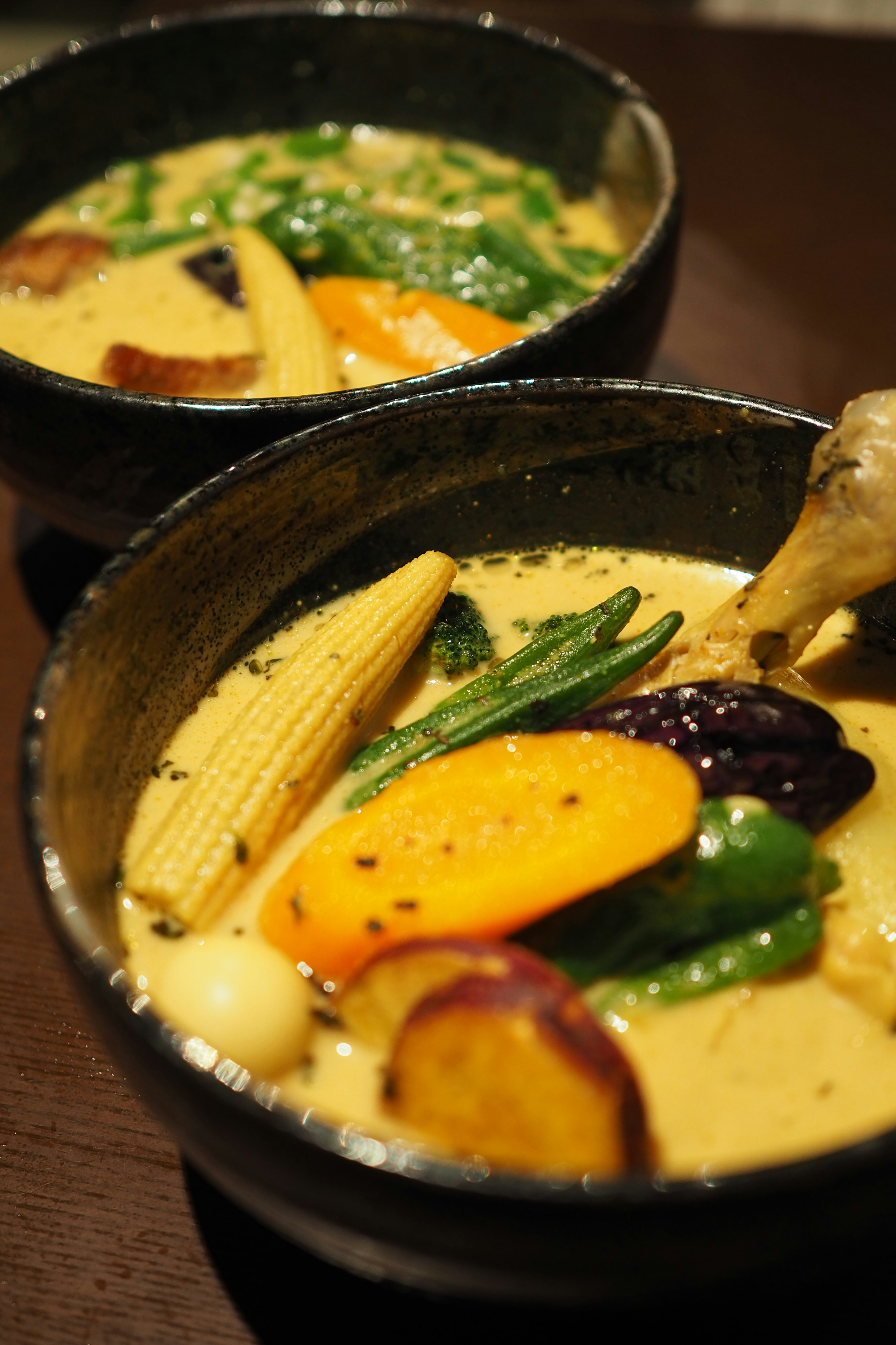 Cuencos negros llenos de sopa de curry de verduras cremosa con verduras variadas