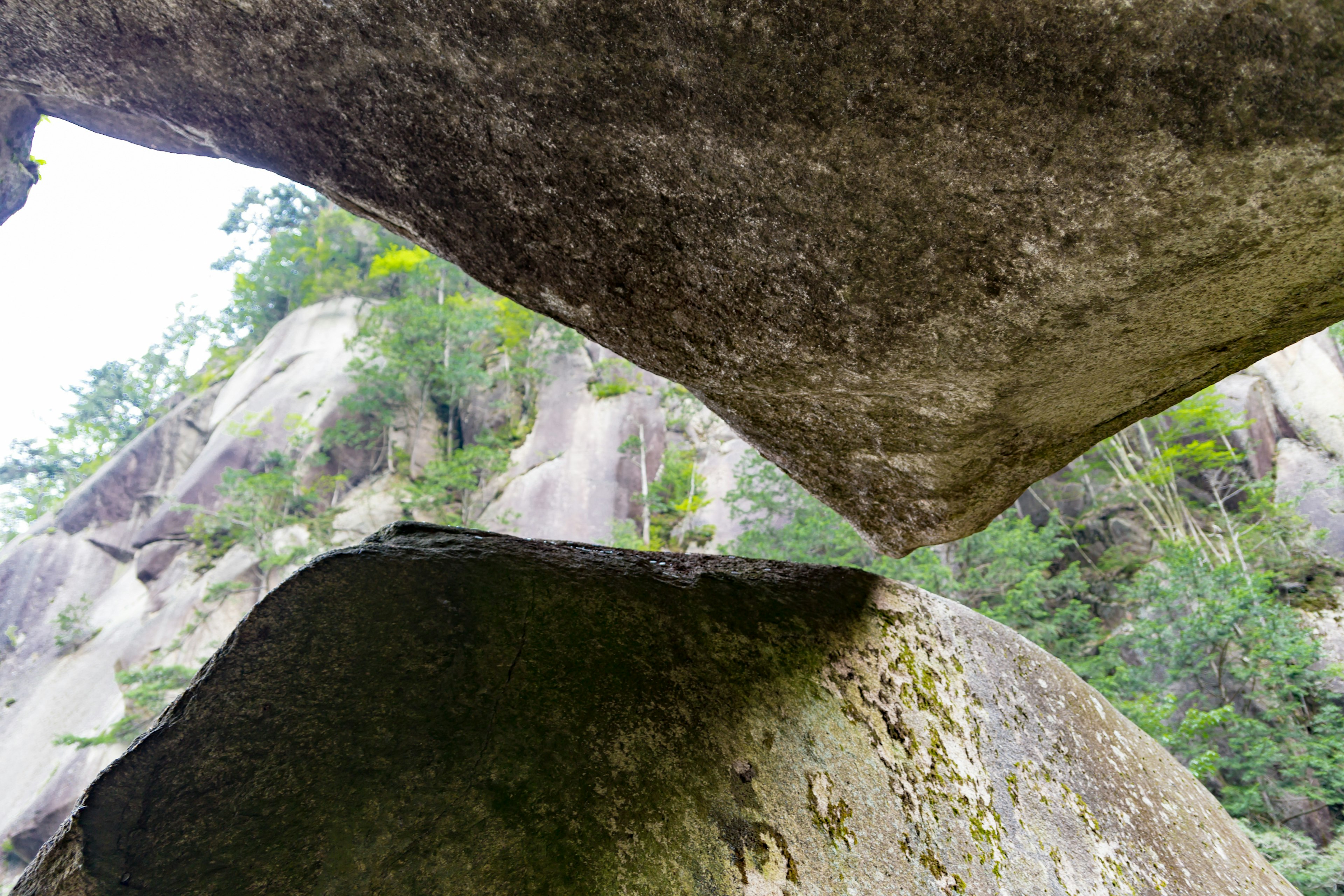 Vista del paisaje verde a través de un espacio entre grandes rocas