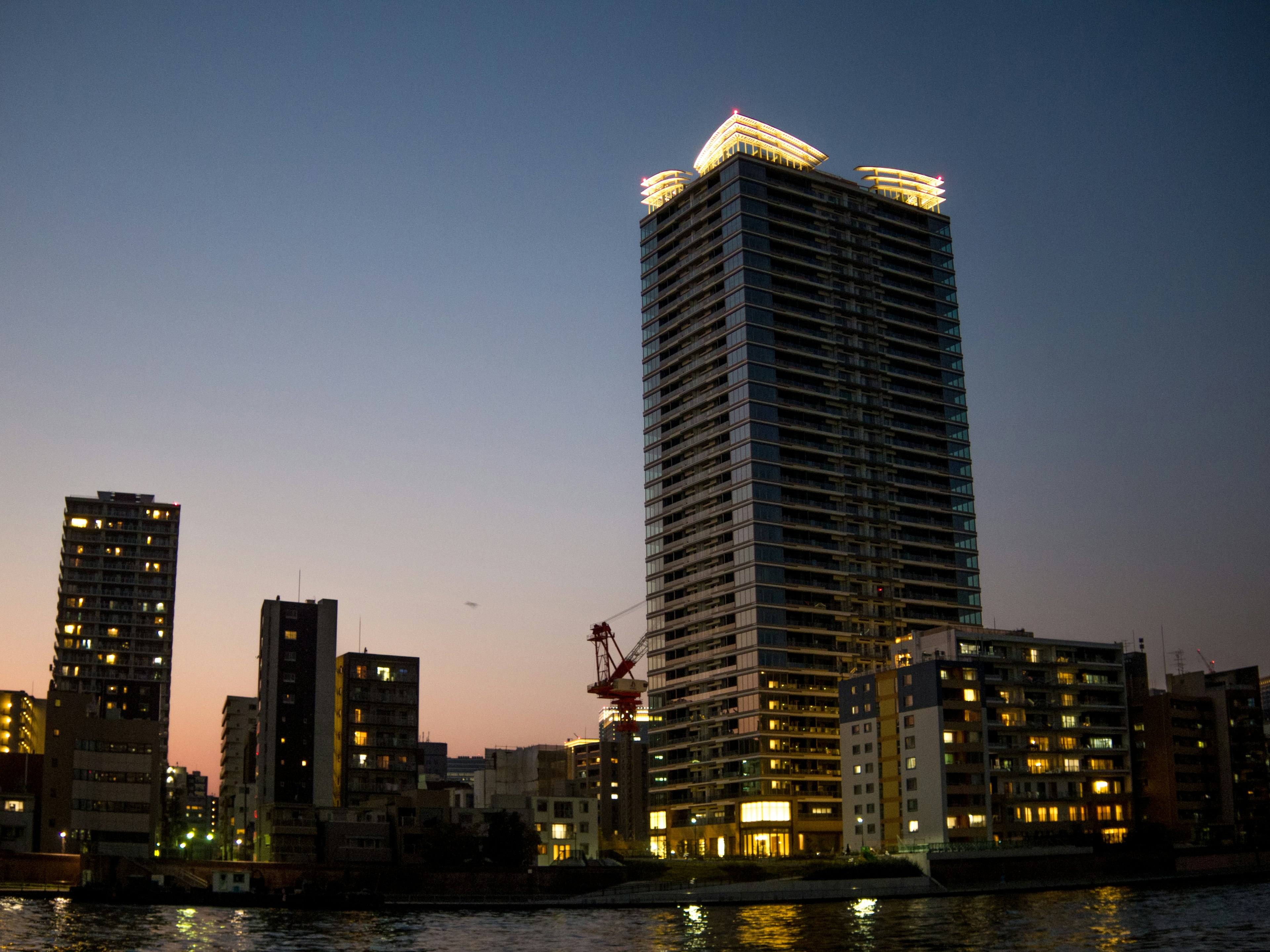 Hochhaus in einer urbanen Landschaft bei Dämmerung mit umliegenden Gebäuden