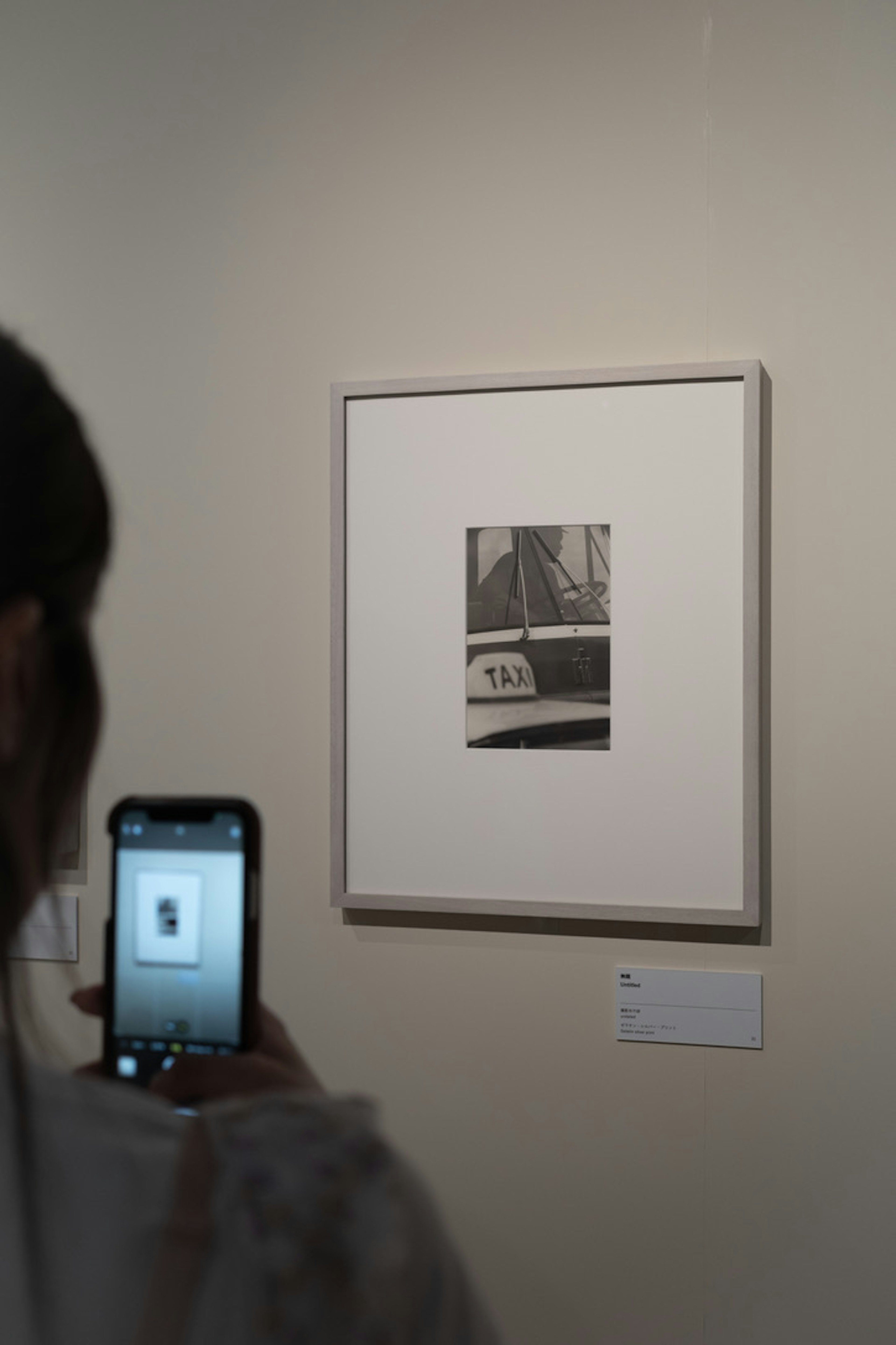 Un visiteur prenant une photo d'une œuvre d'art en noir et blanc exposée dans une galerie