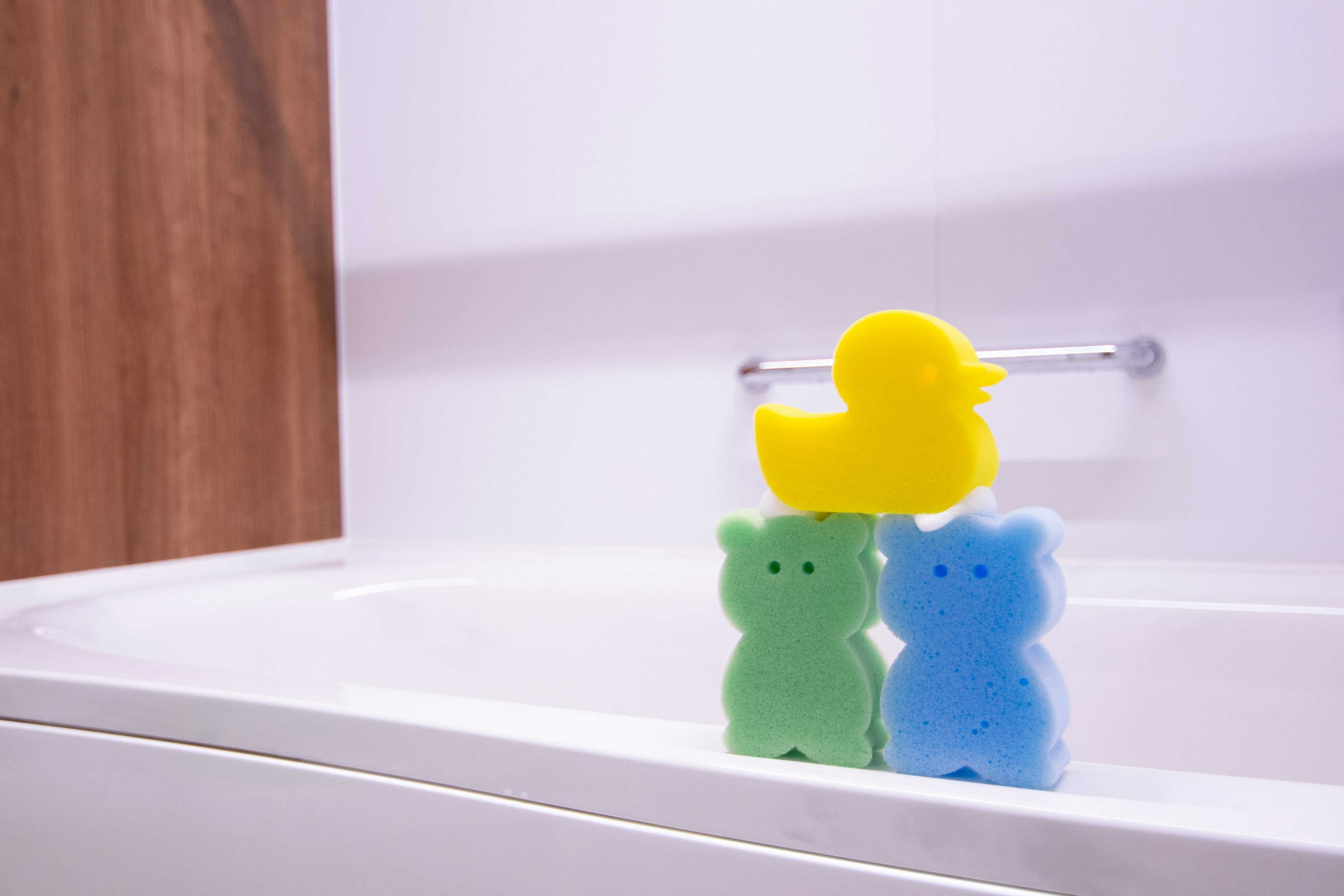 Colorful sponge toys including a duck and bear shapes in a bathtub