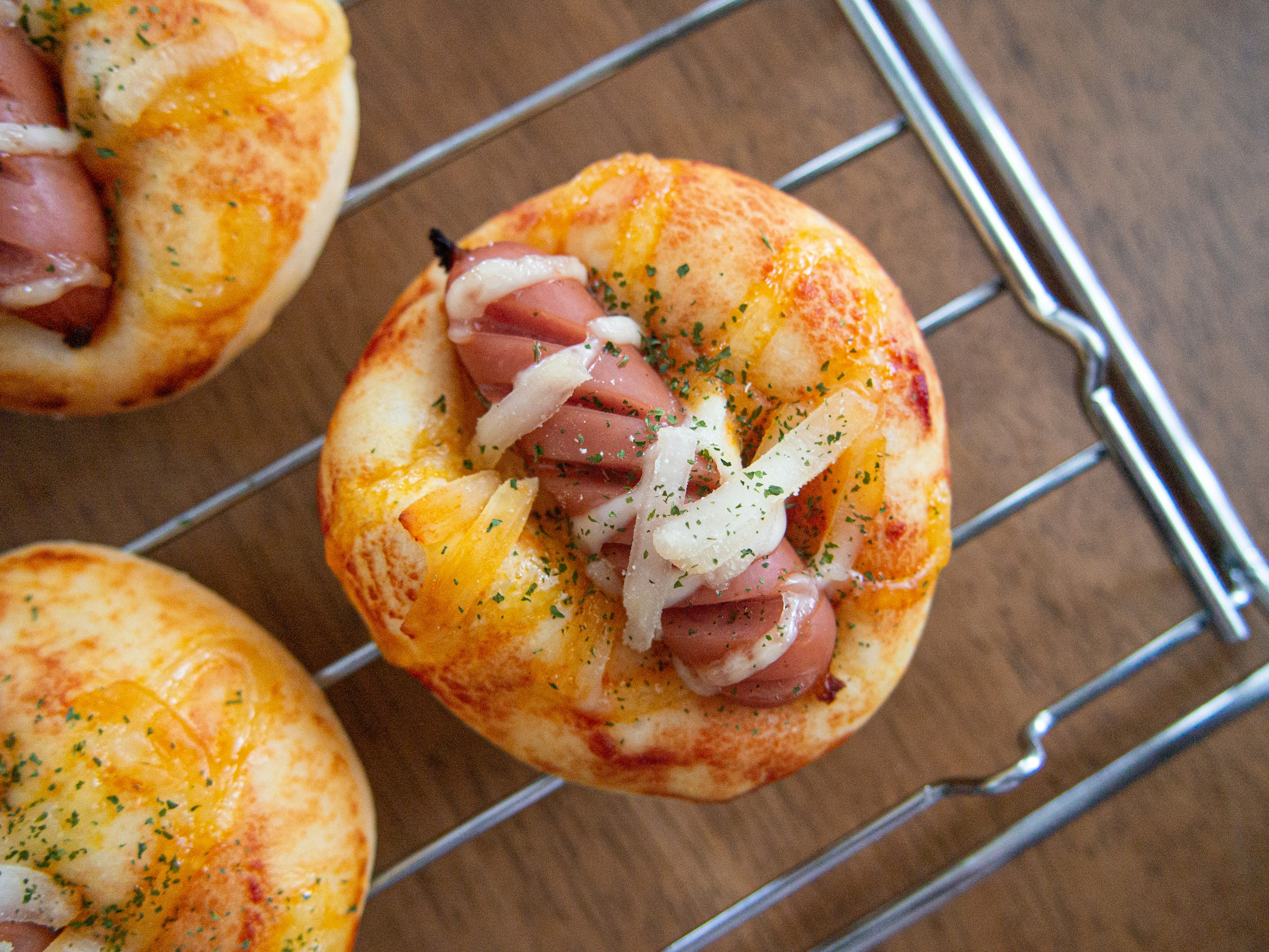 Mini pizze appena sfornate con formaggio e salsiccia su una griglia