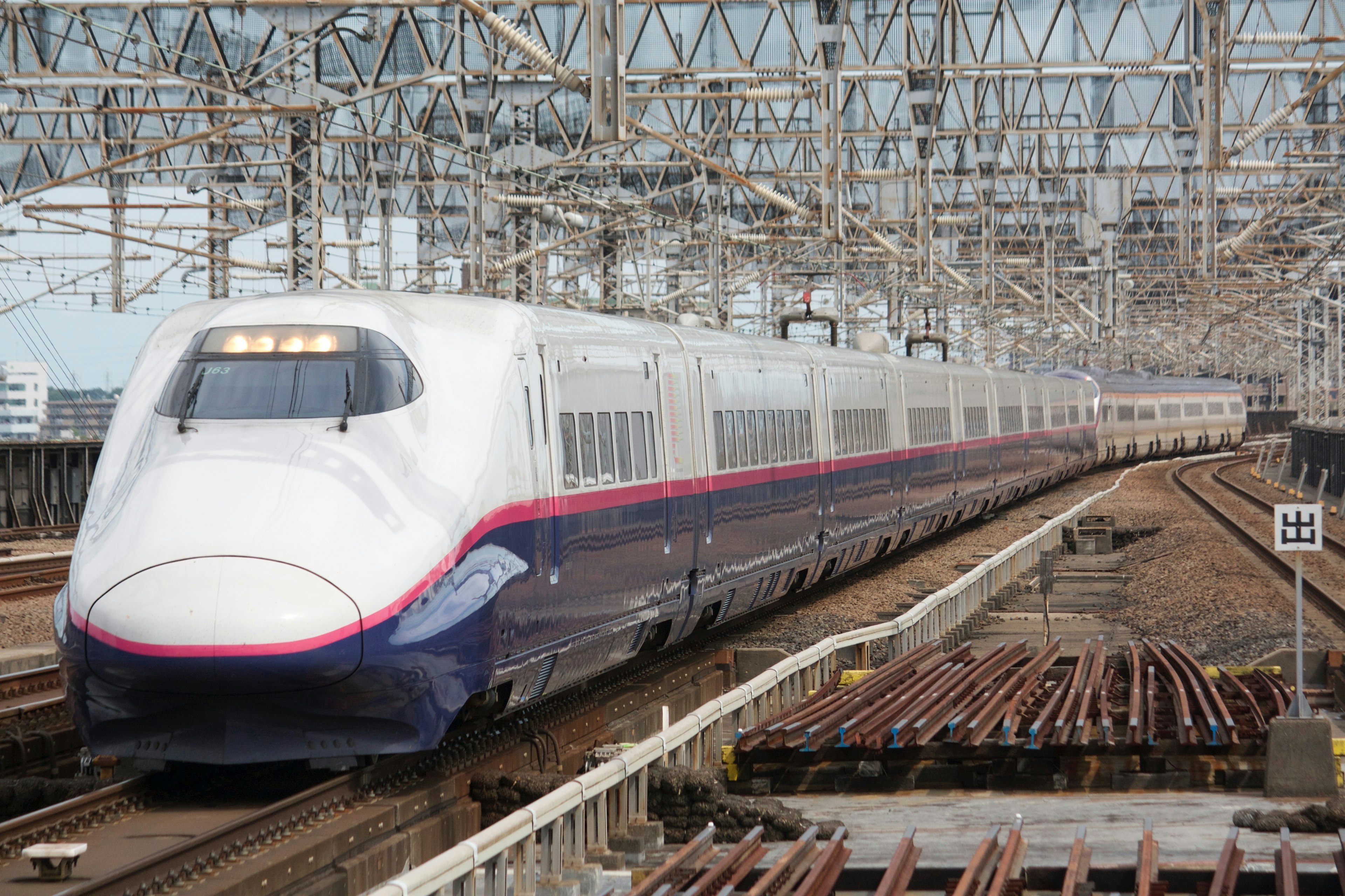 Shinkansen train traveling under railway structures