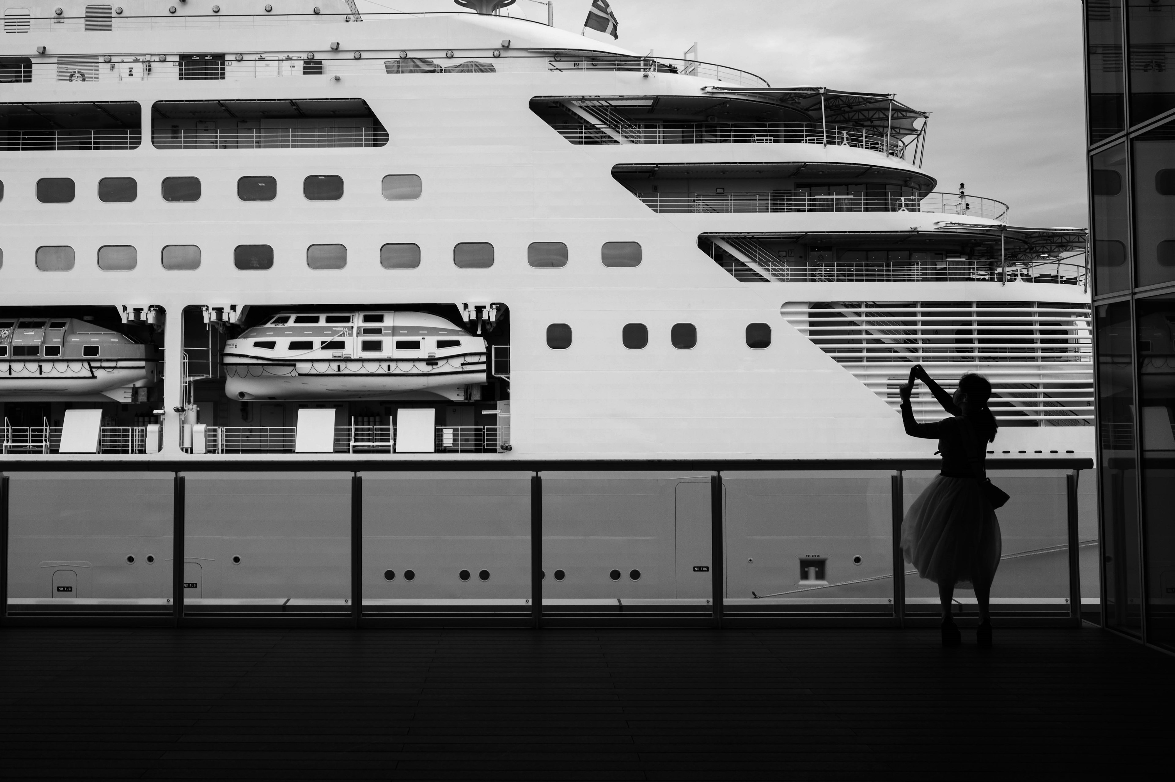 Silhouette eines Kreuzfahrtschiffes mit einer Frau, die auf einem Balkon ein Instrument spielt