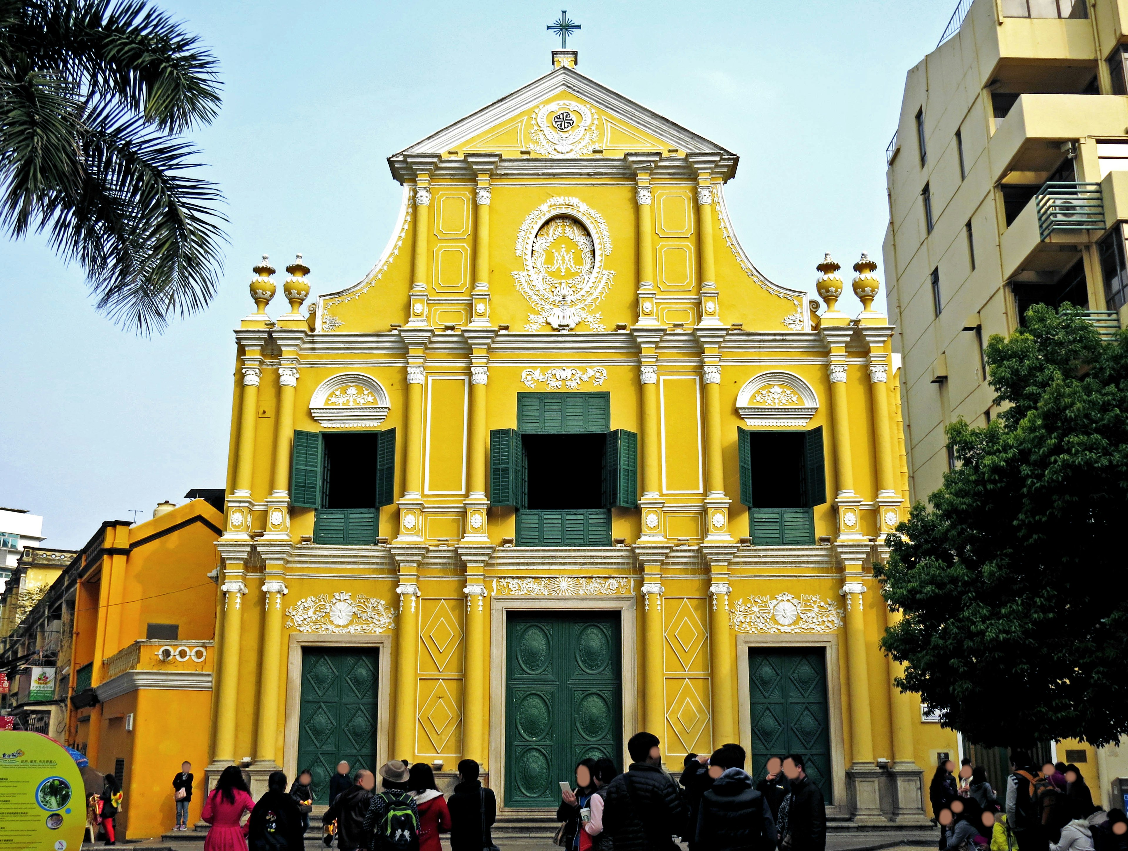 Facciata colorata di una chiesa gialla con persone intorno