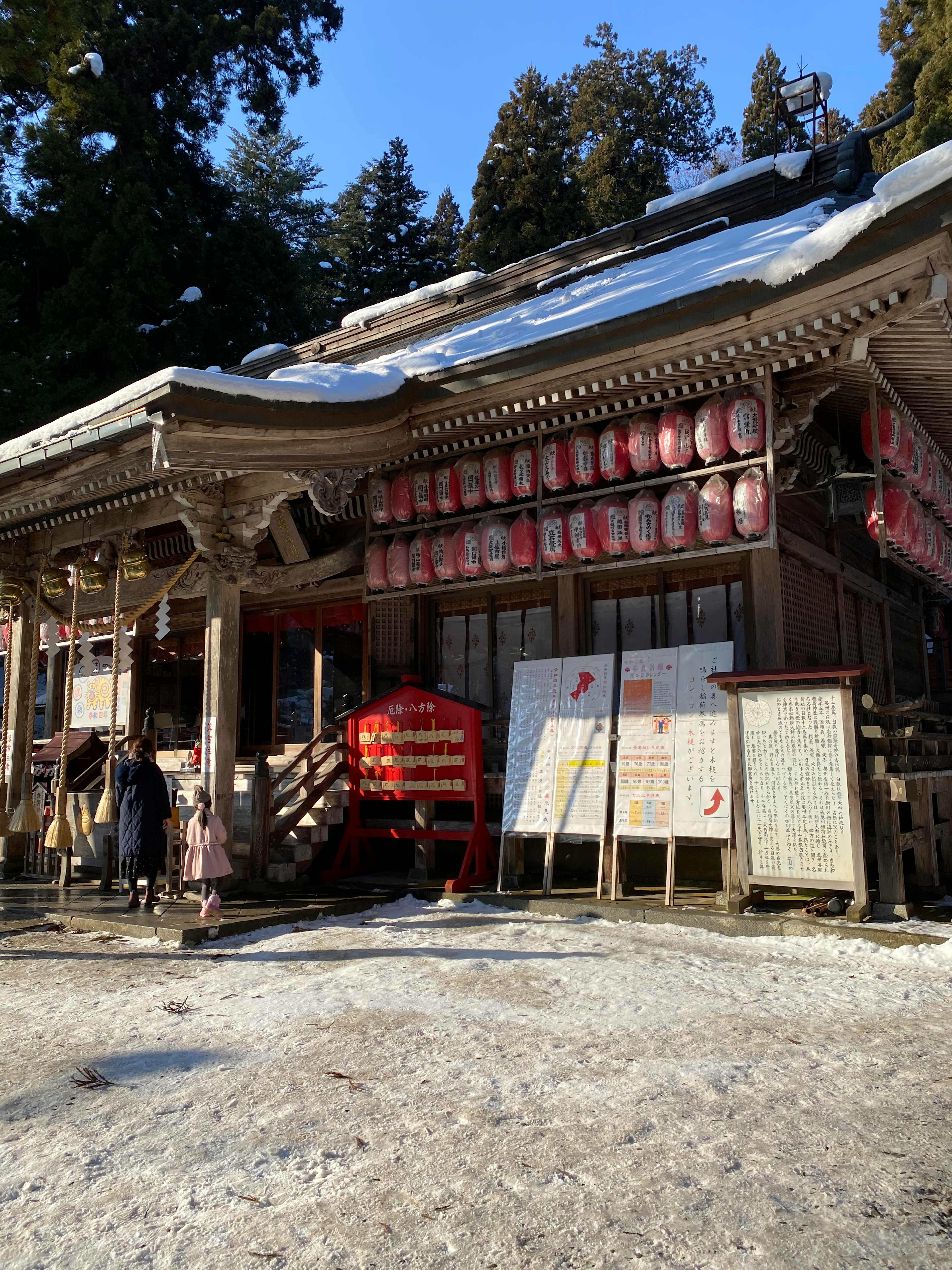 雪に覆われた神社の外観 赤い提灯と看板が特徴的