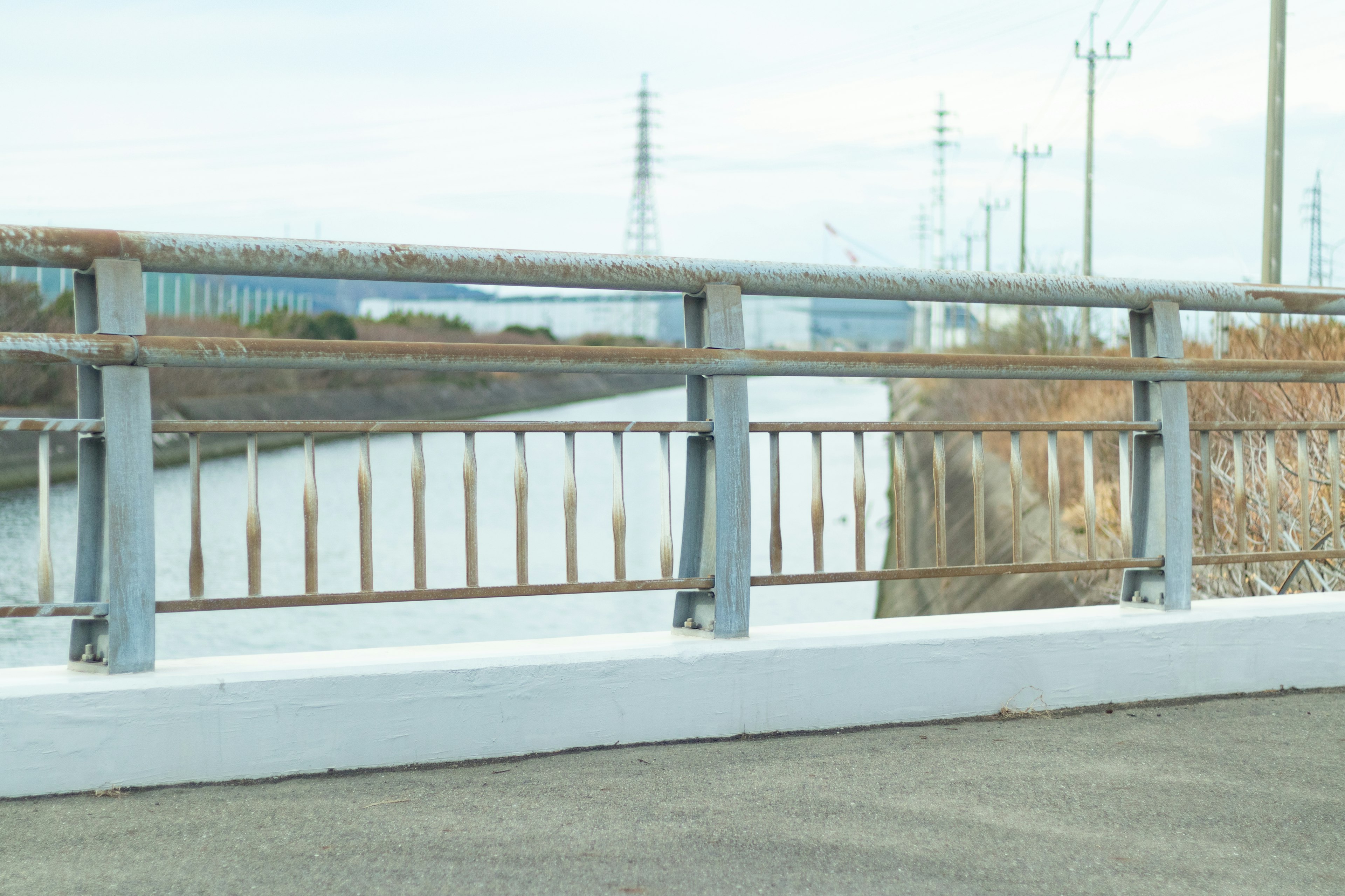 Metal railing near a river with a concrete road