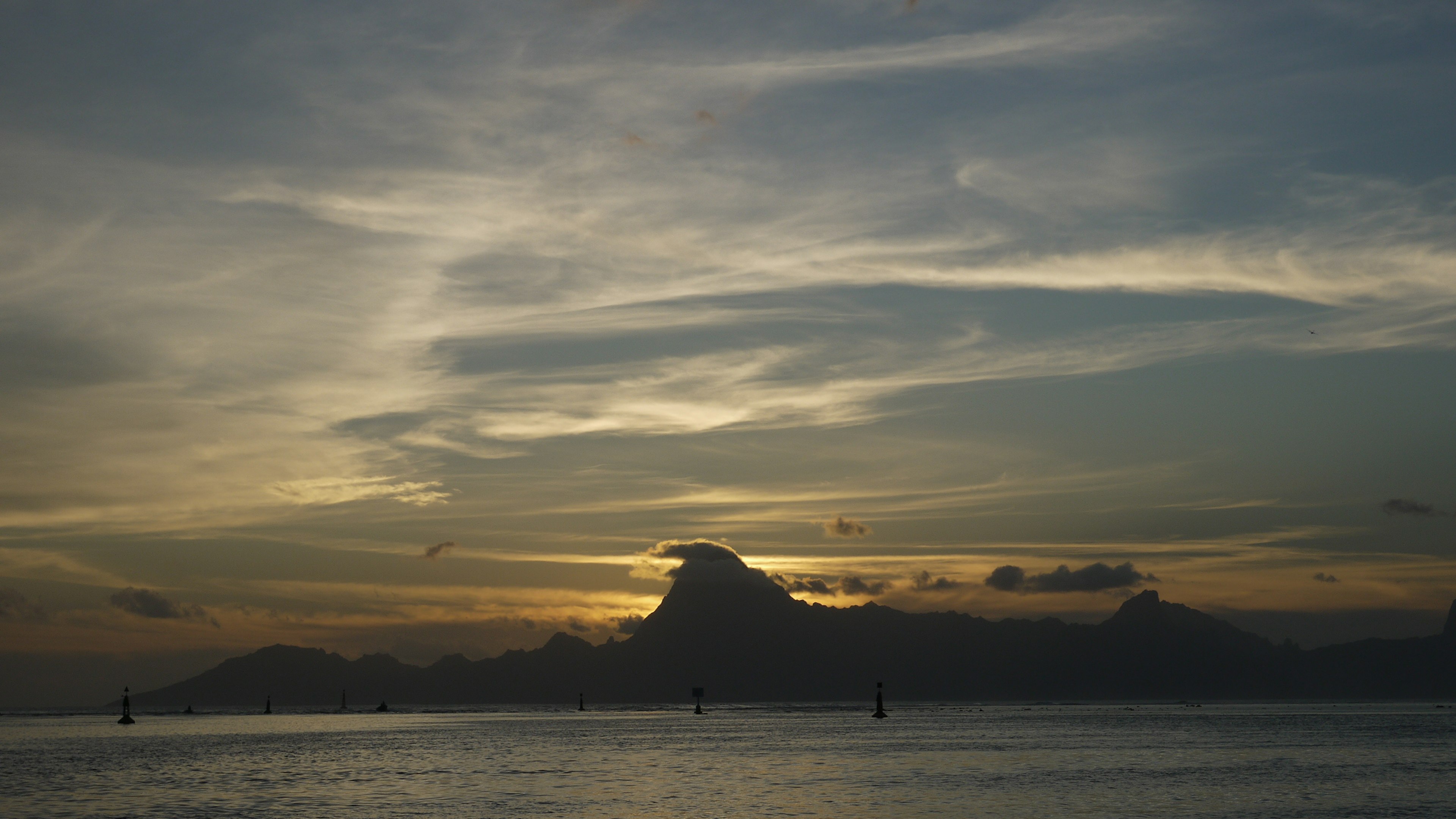 Scenic view of a silhouette of mountains and ocean during sunset