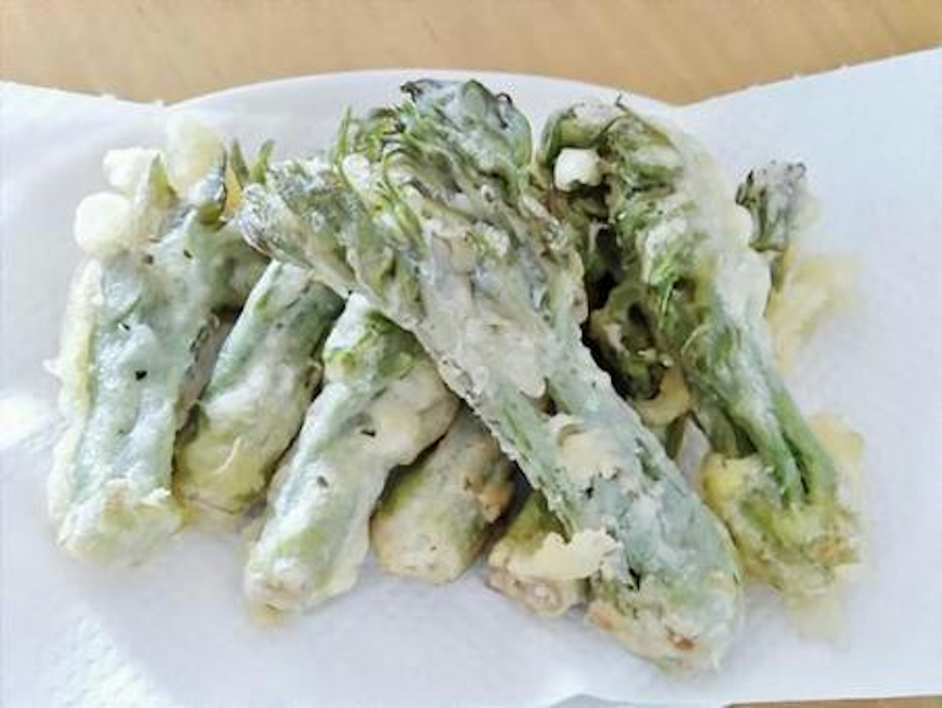 Sekelompok asparagus goreng di atas handuk kertas putih