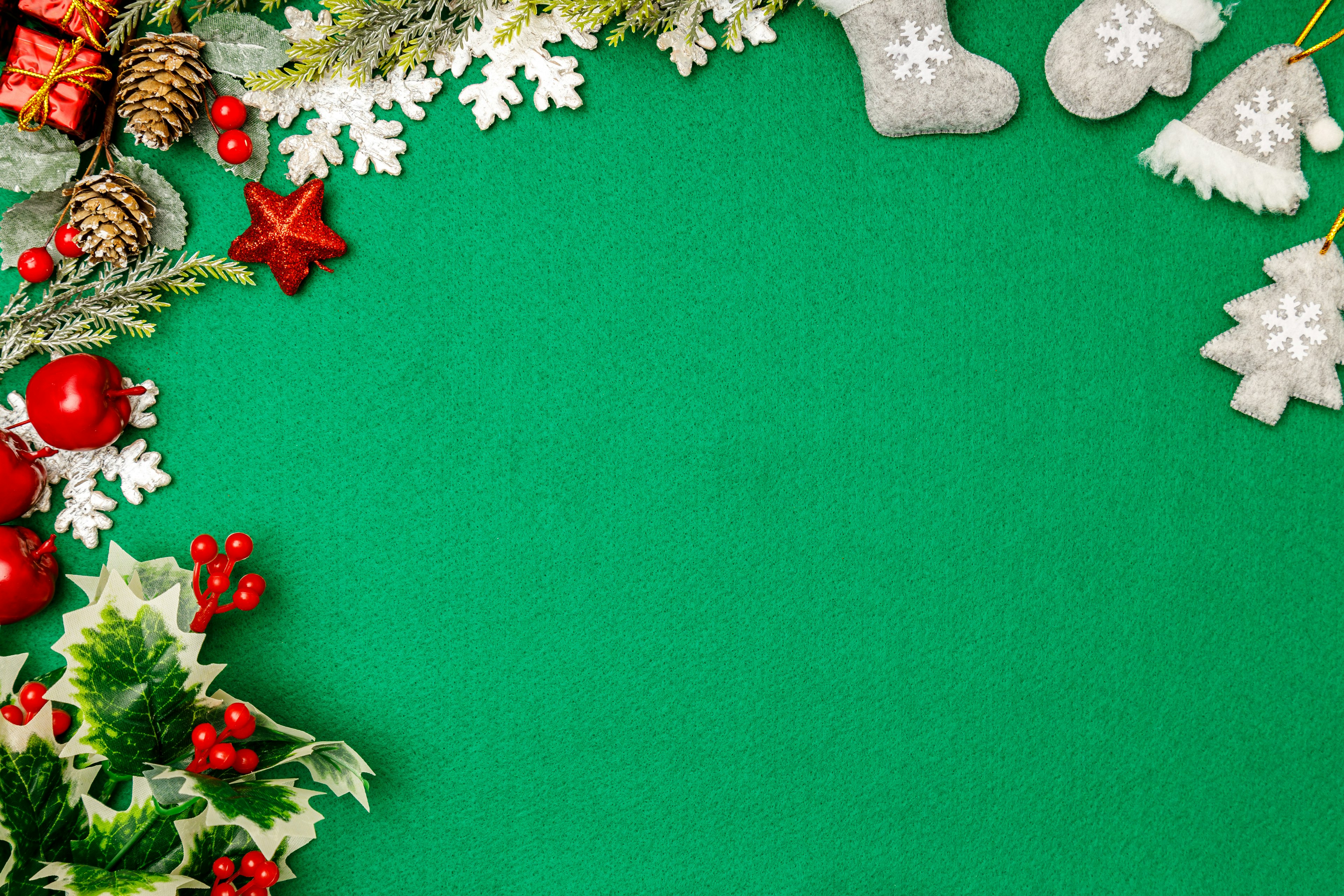 Christmas decorations including red ornaments and snowflakes arranged on a green background