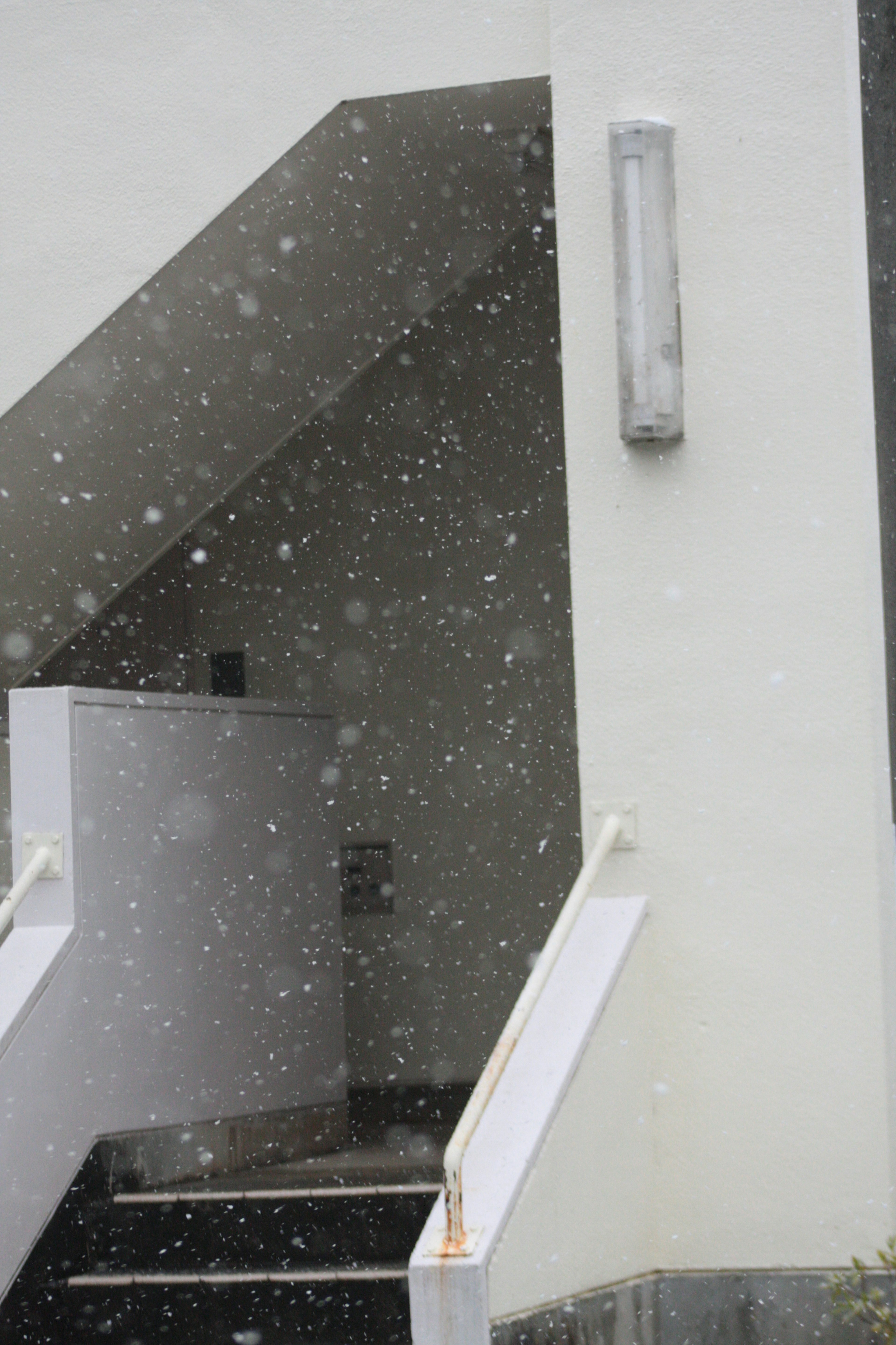 Escalera y pared de un edificio blanco durante la nevada