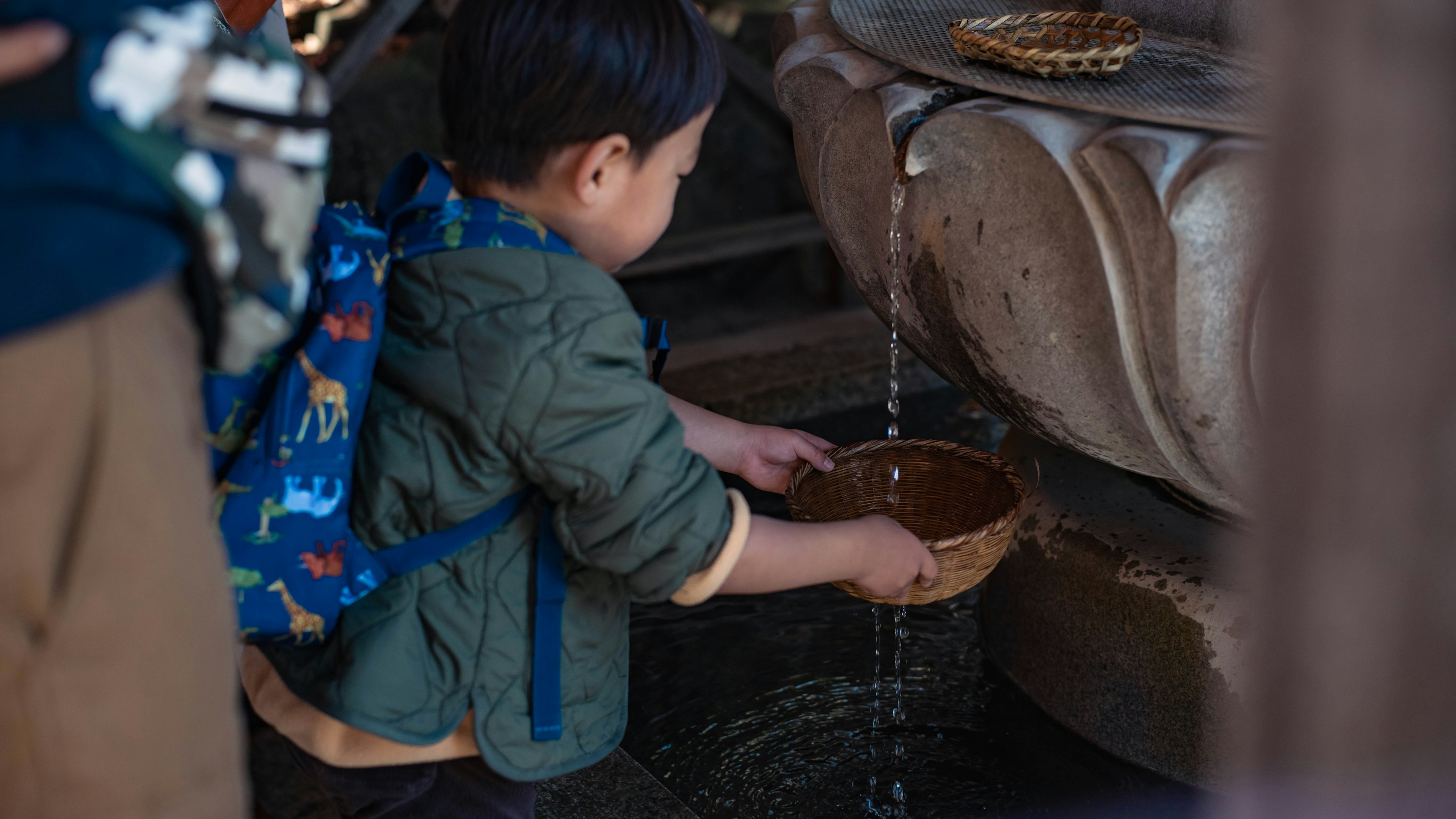 Kind, das Wasser mit einer Schüssel aus einem Brunnen schöpft und den Fluss genießt