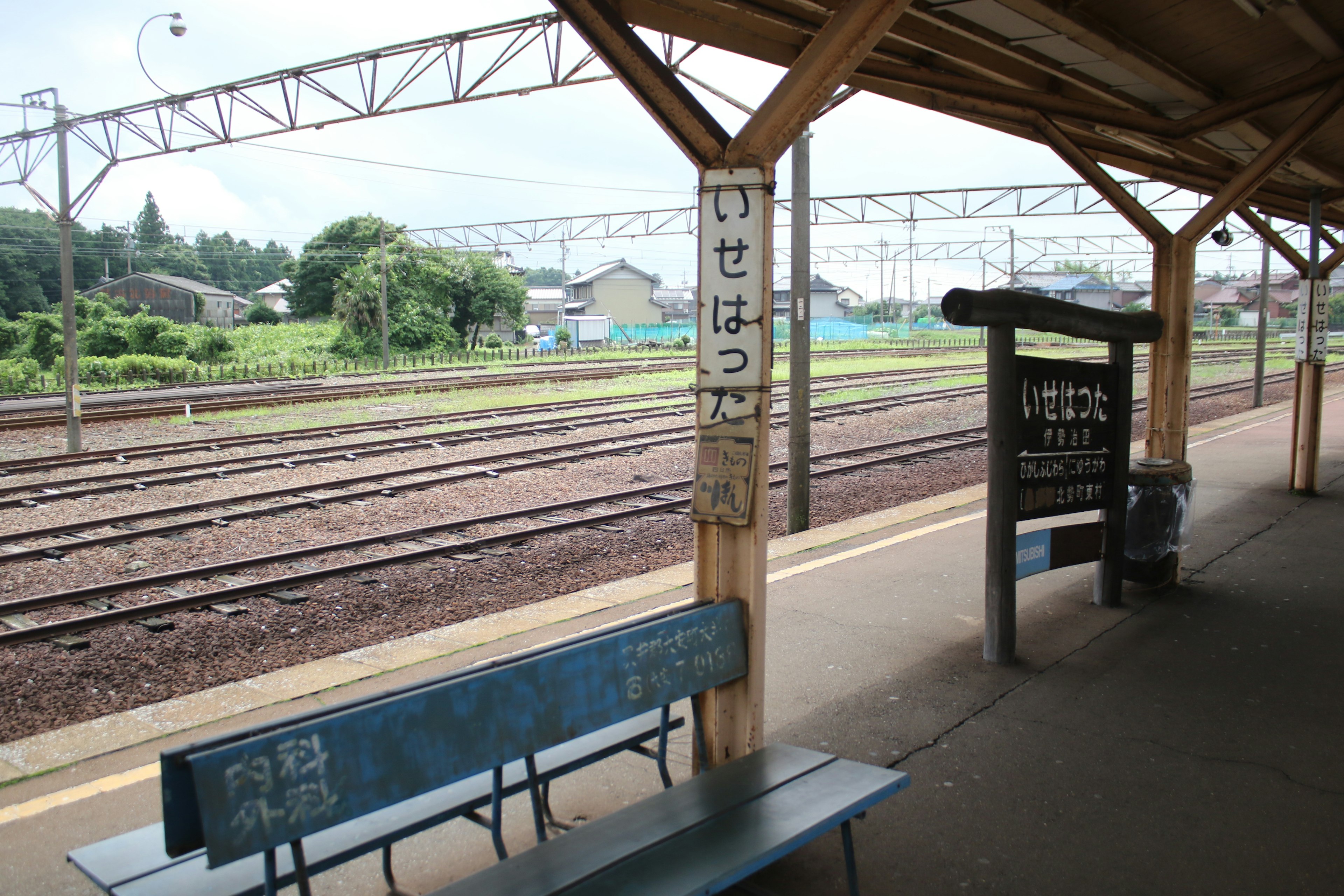 Bangku biru di platform Stasiun Isehara dengan pemandangan sekitarnya