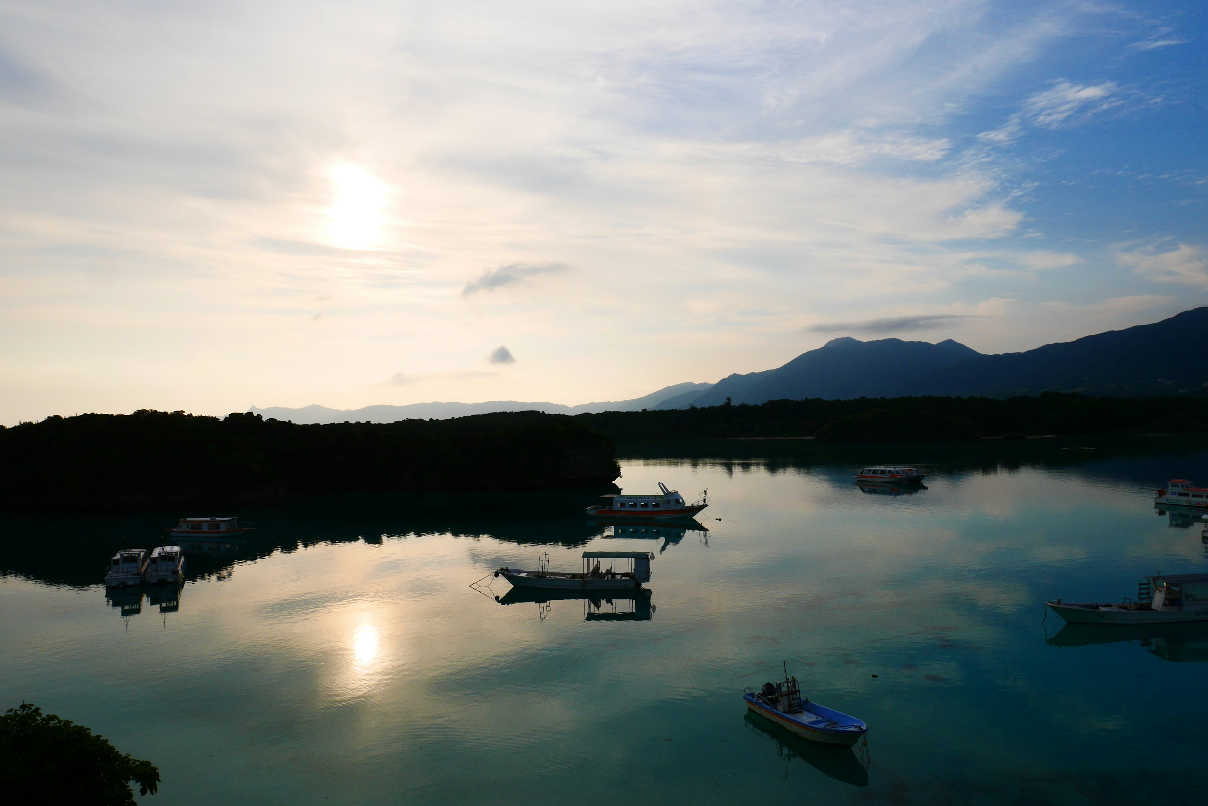 Agua tranquila reflejando montañas y botes