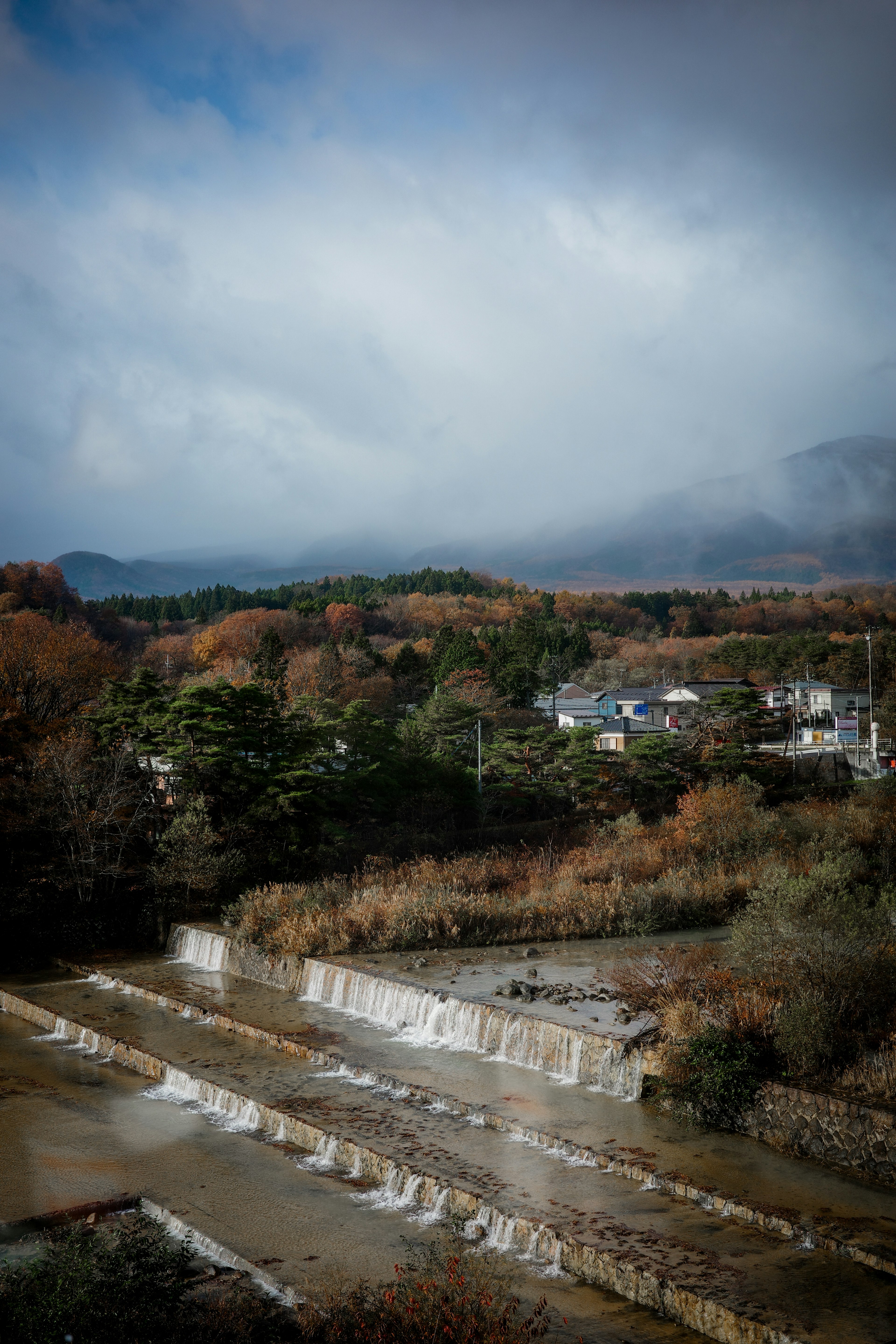 秋の風景が広がる川沿いの風景に雲がかかる