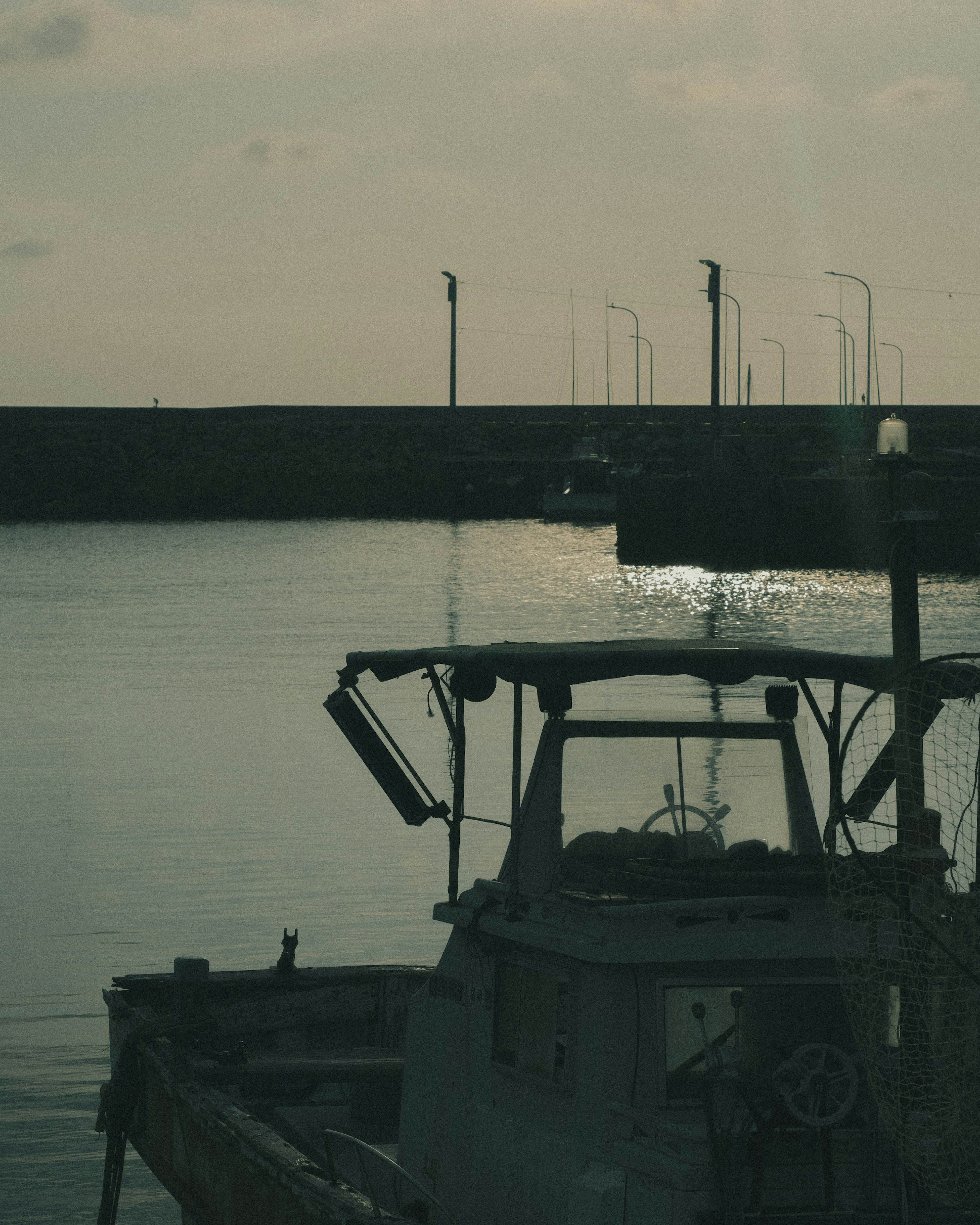 Silhouette d'un bateau de pêche amarré dans un port calme avec de l'eau calme