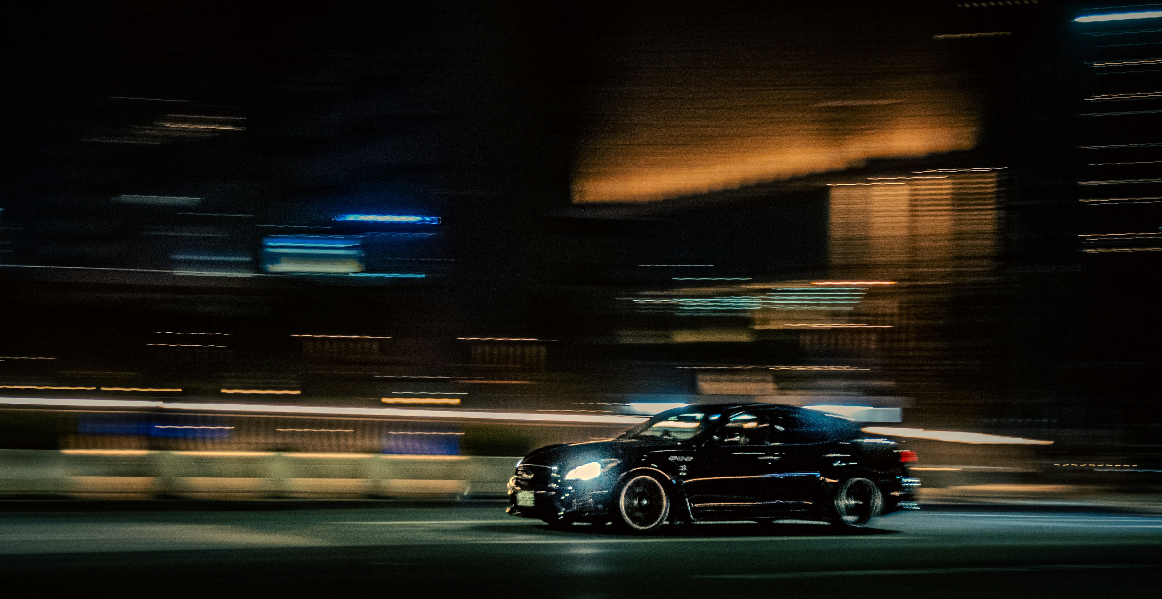 Dynamic image of a black sports car racing through a city at night