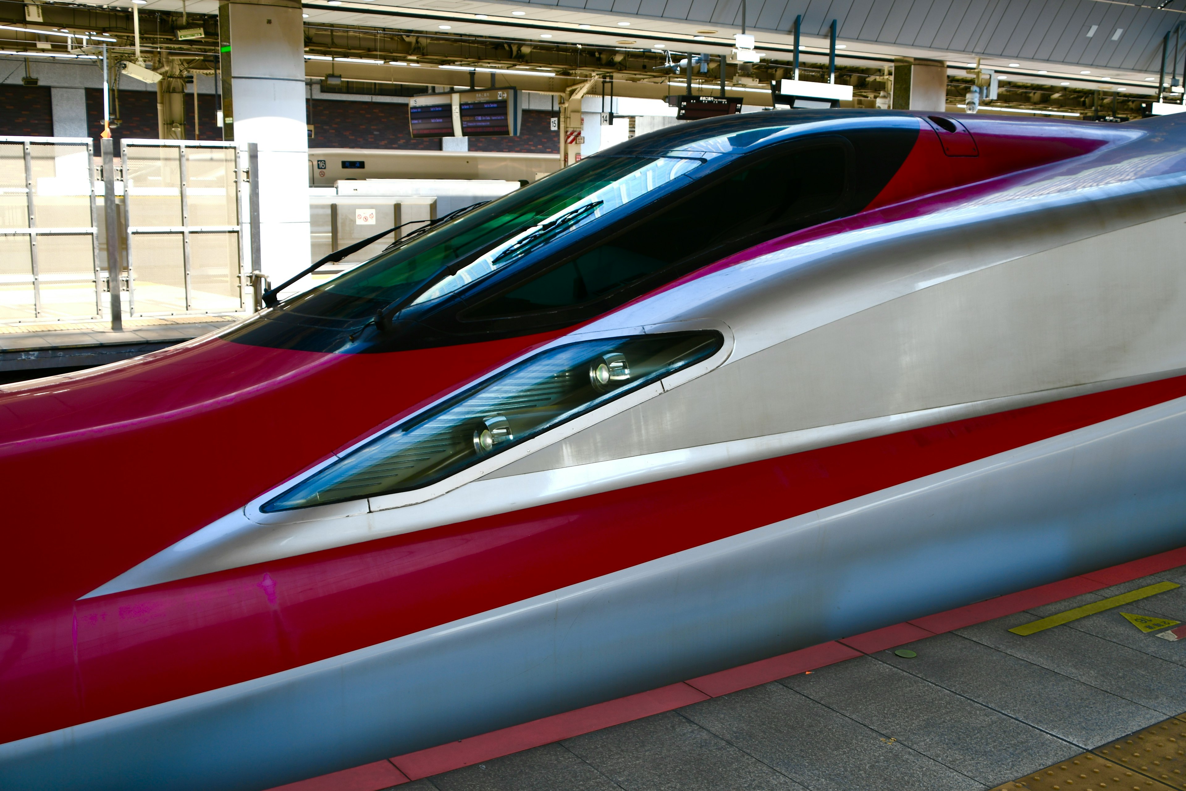 Vorderansicht eines roten und weißen Shinkansen an einem Bahnhof