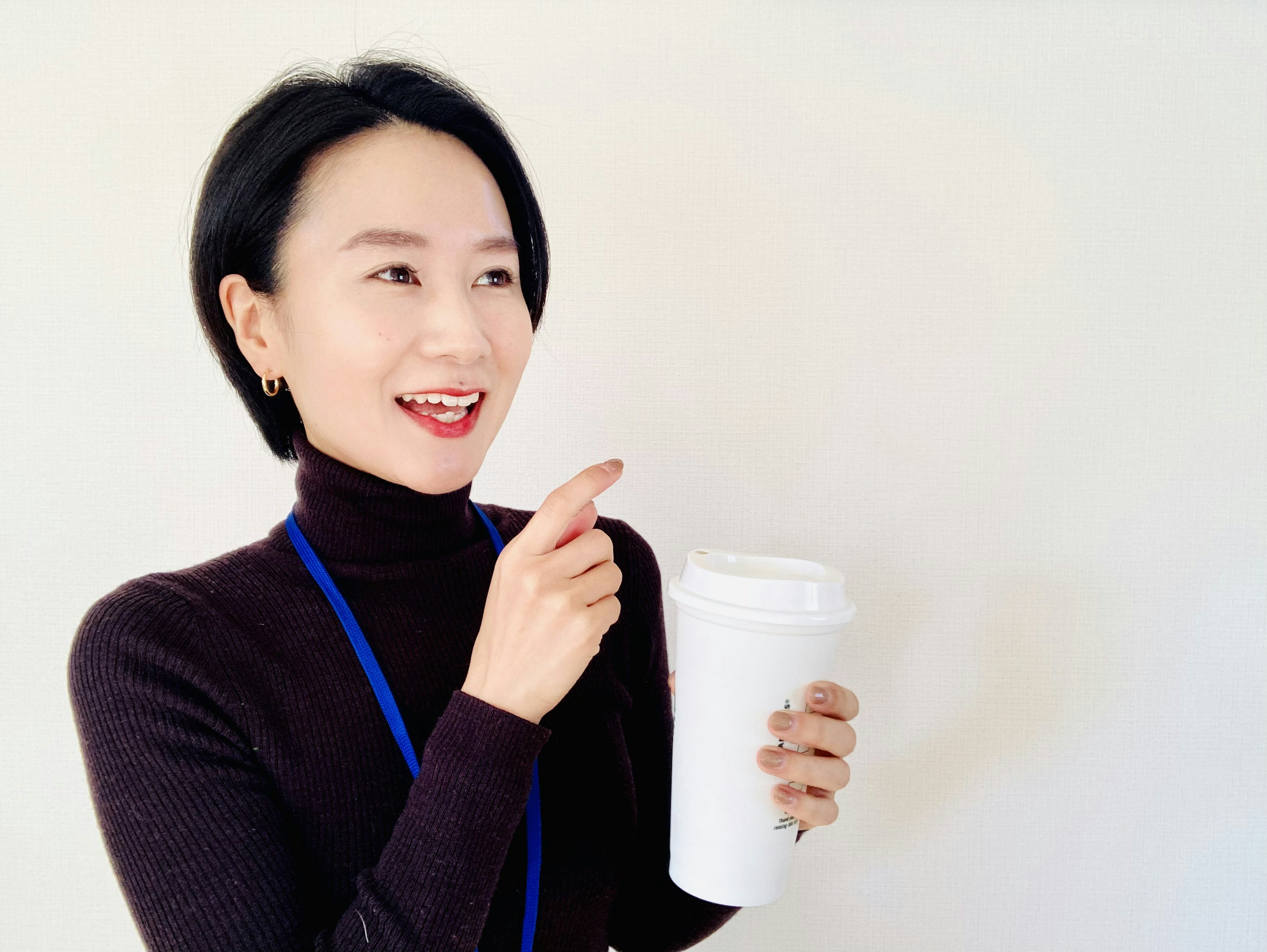 女性がコーヒーカップを持って微笑んでいる