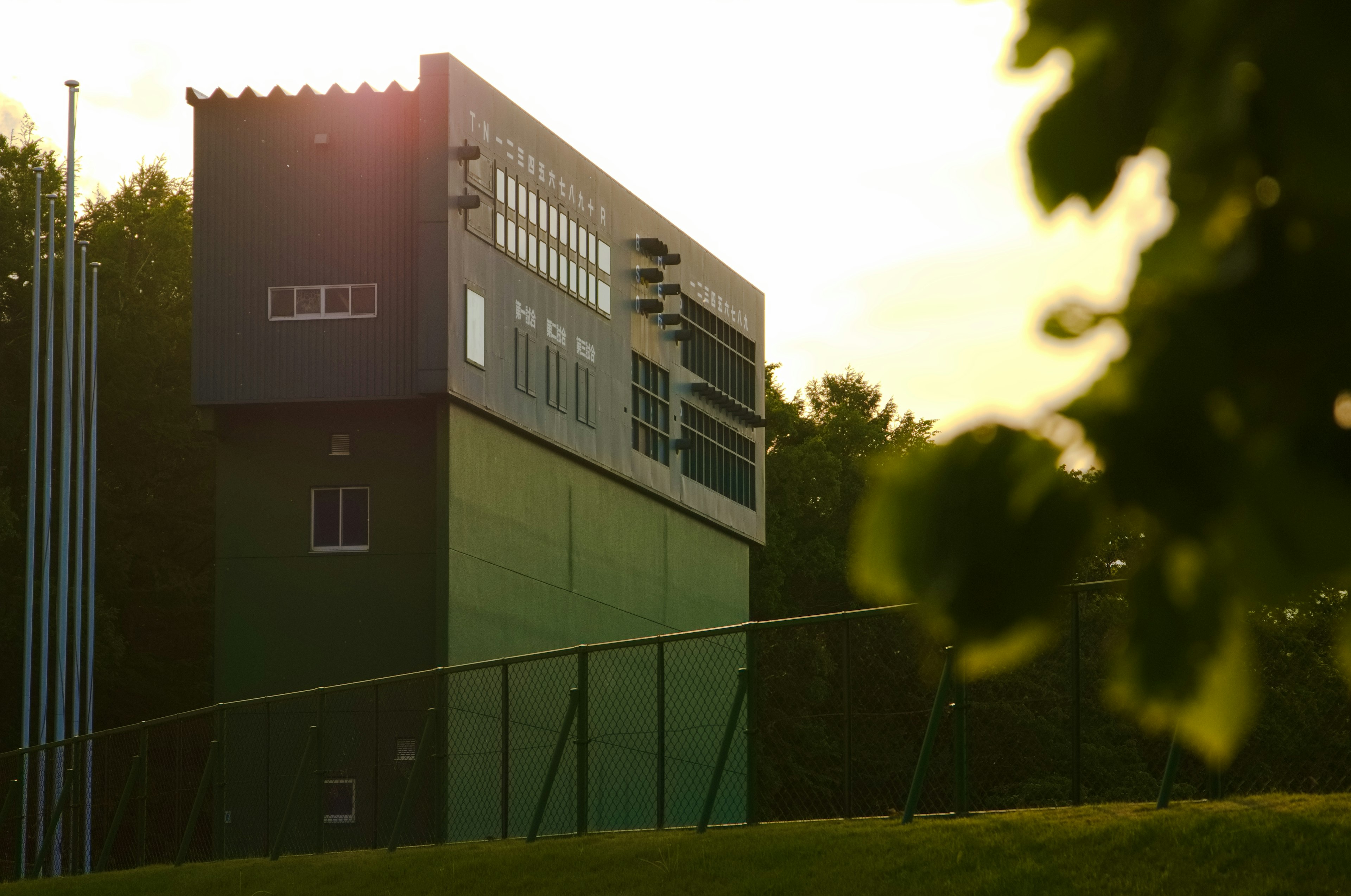 Edificio de estadio deportivo verde con marcador iluminado por el atardecer