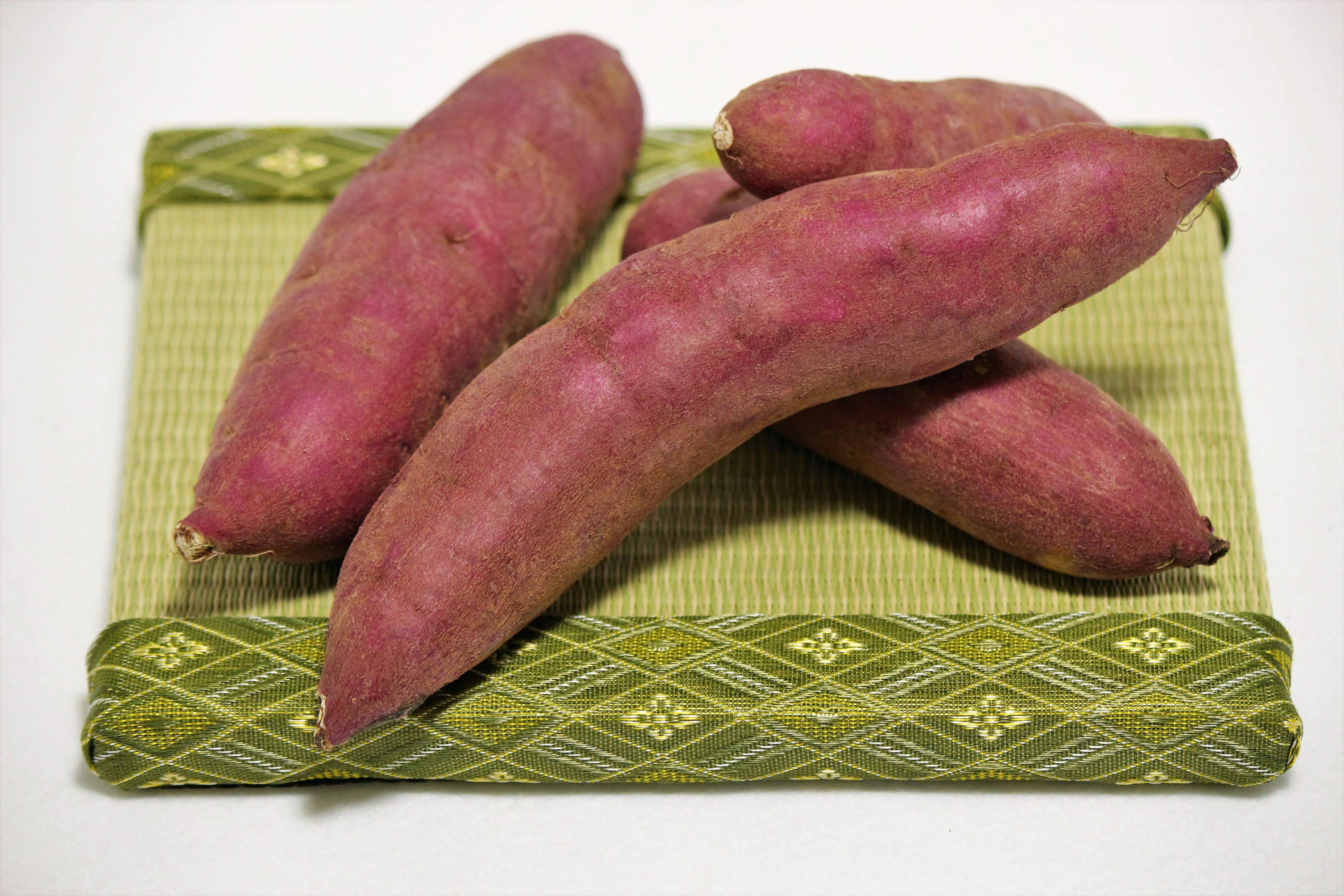 Purple sweet potatoes arranged on a green mat