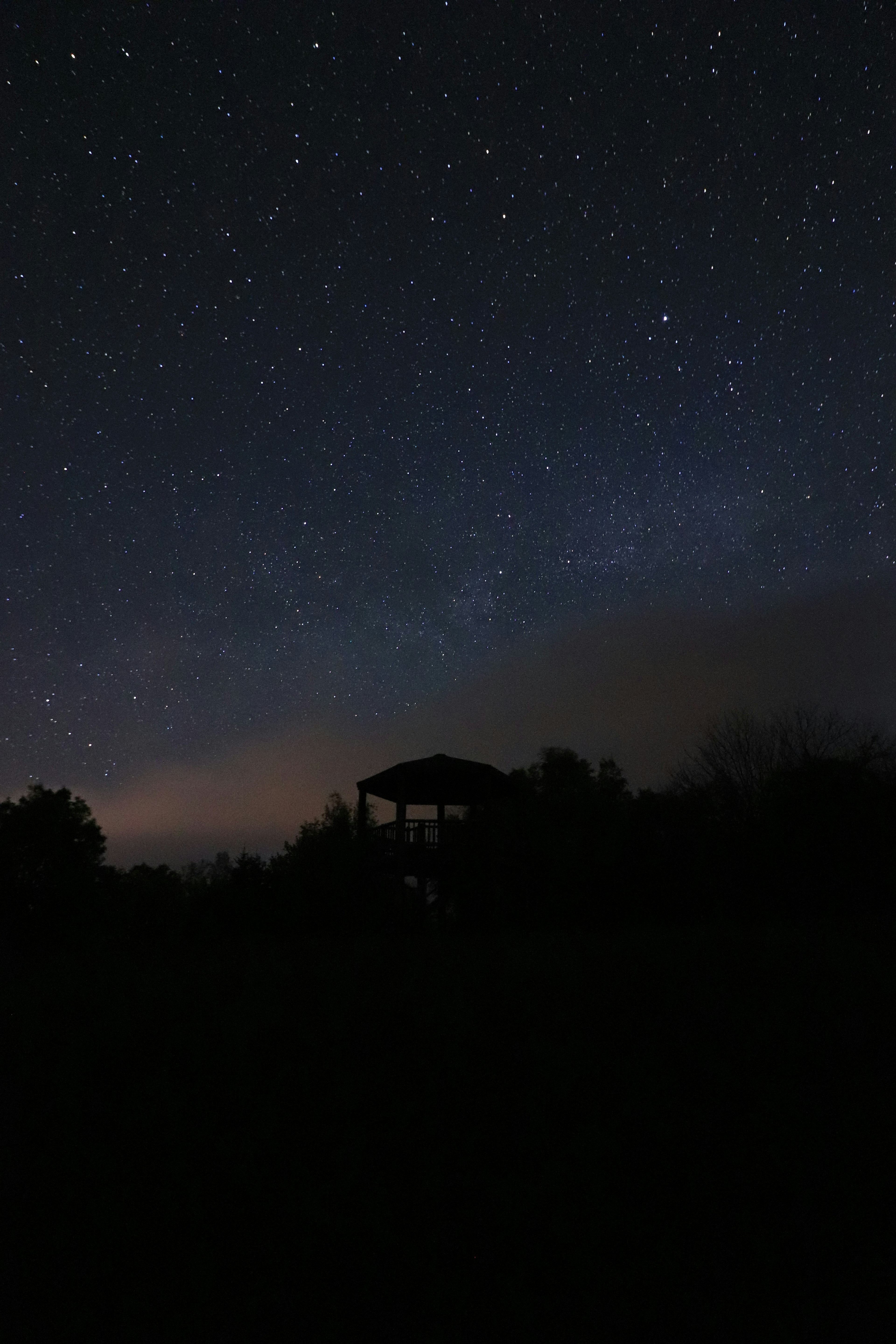 Night sky filled with stars and silhouette of a small gazebo