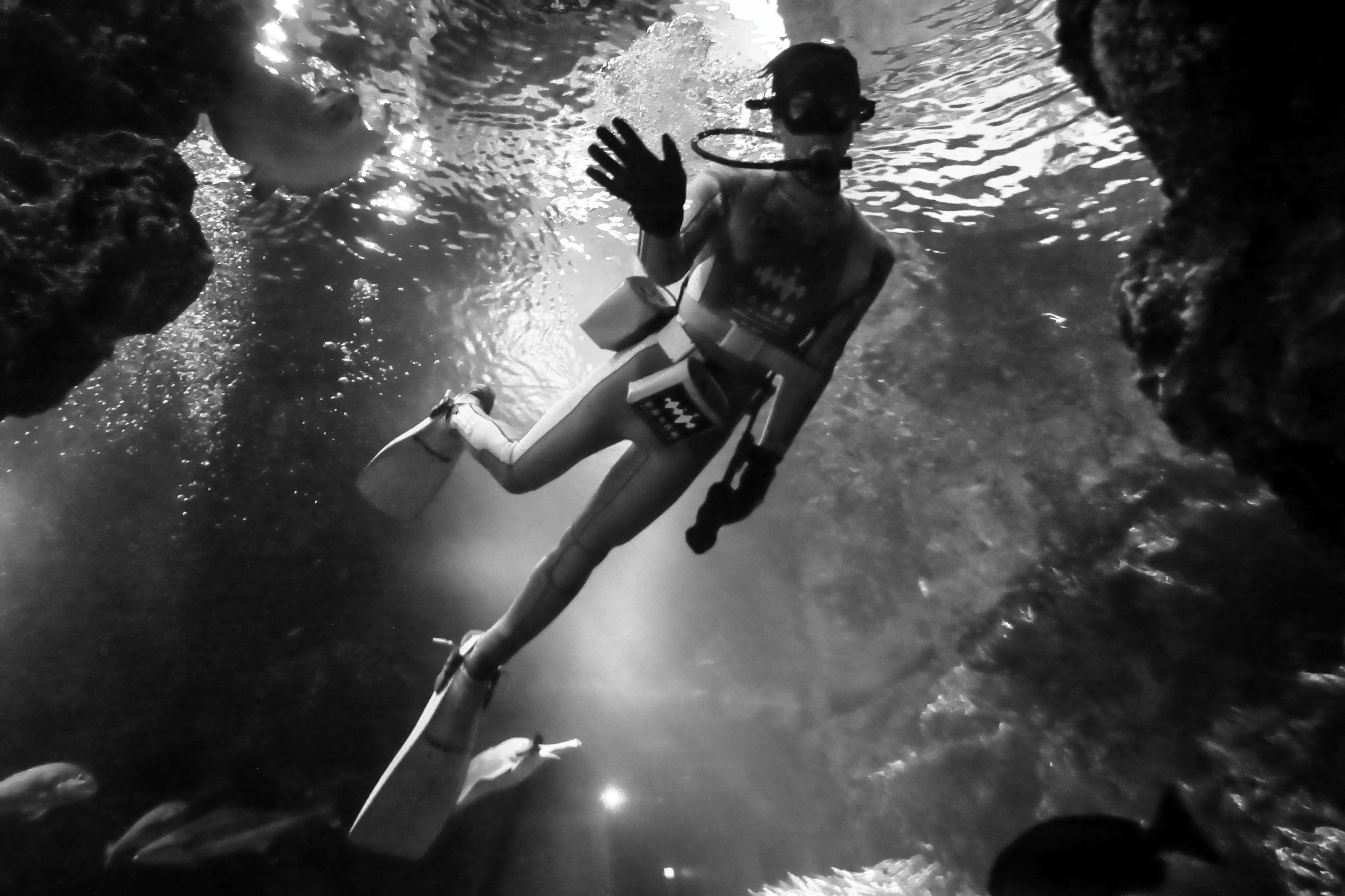 Plongeur nageant sous l'eau dans une photo en noir et blanc avec une atmosphère éthérée