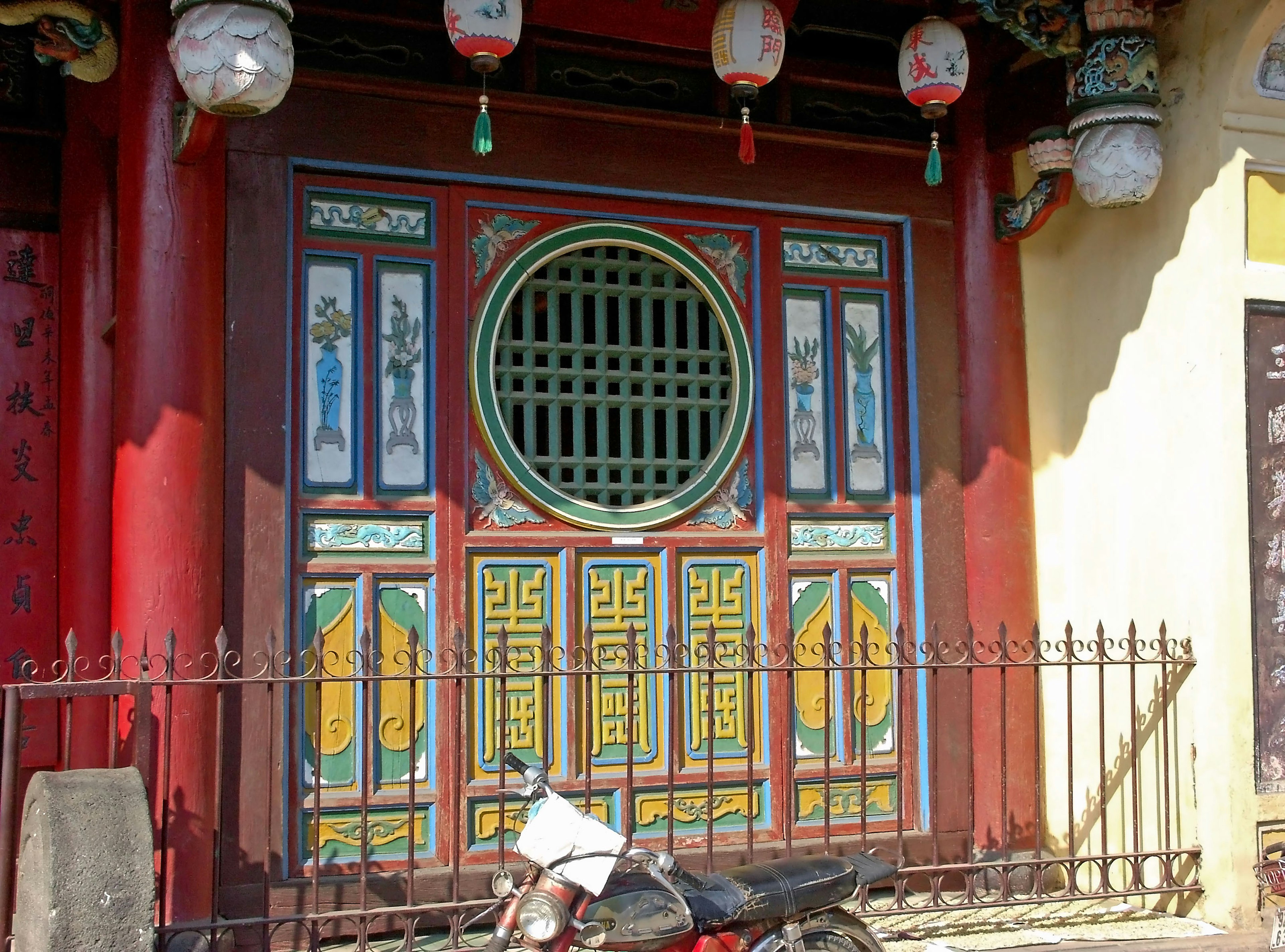 Porta in stile cinese colorata con decorazioni intricate e muro rosso