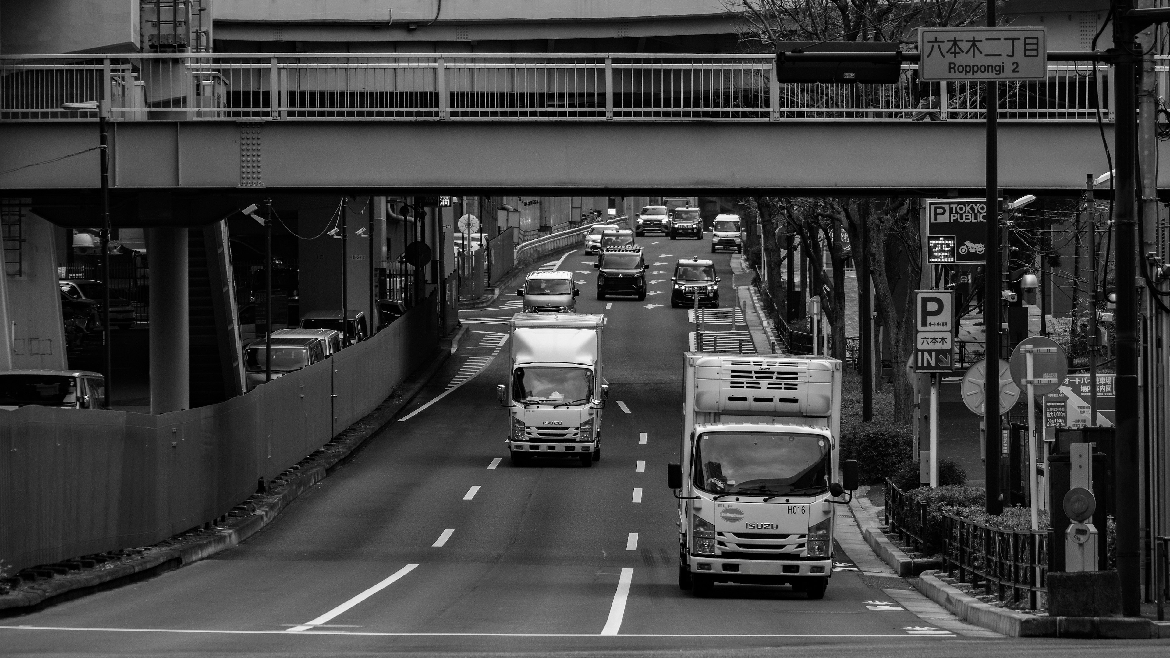 Scena urbana in bianco e nero con camion su una strada e un cavalcavia