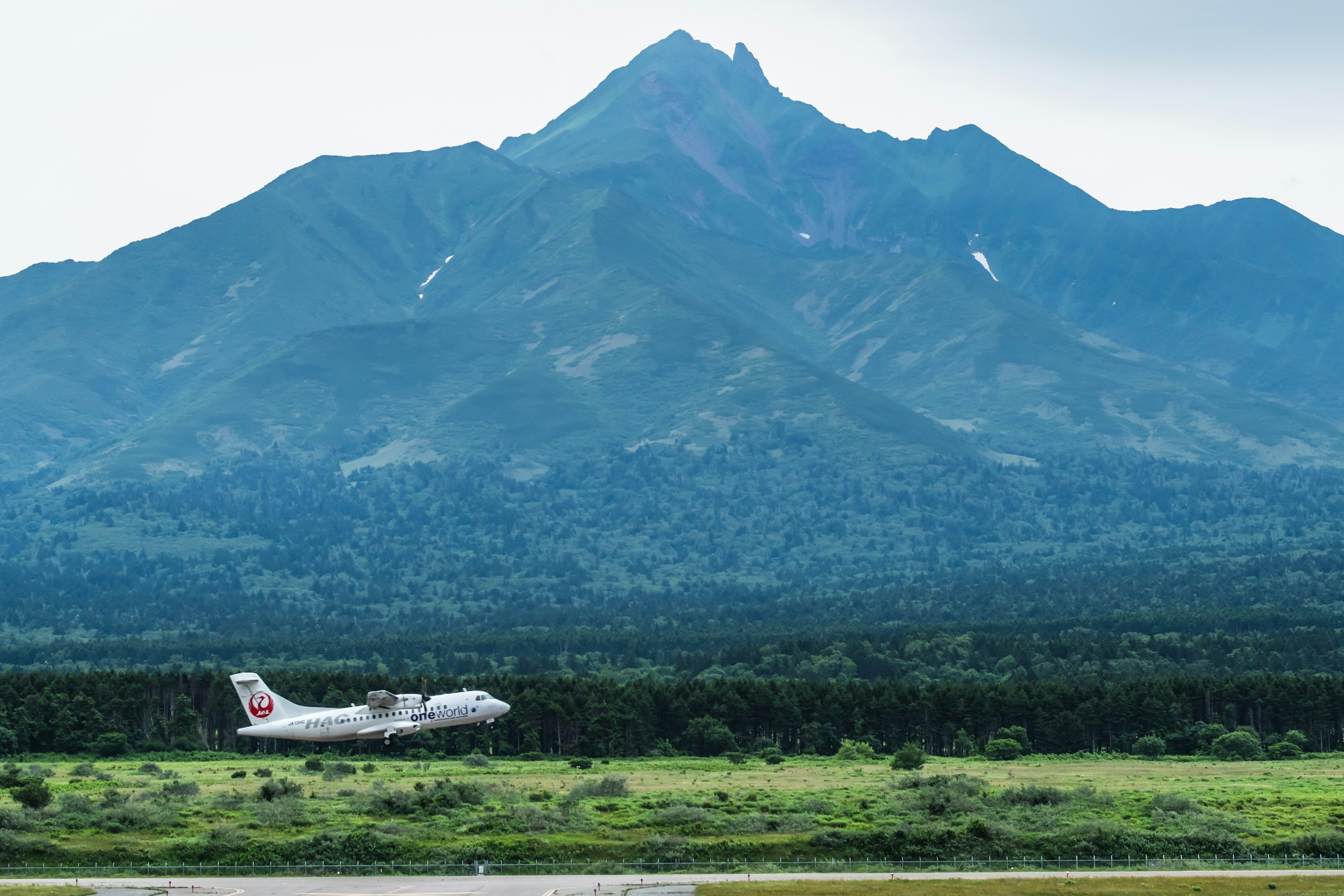 Piccolo aereo che decolla da una pista aeroportuale con montagne sullo sfondo