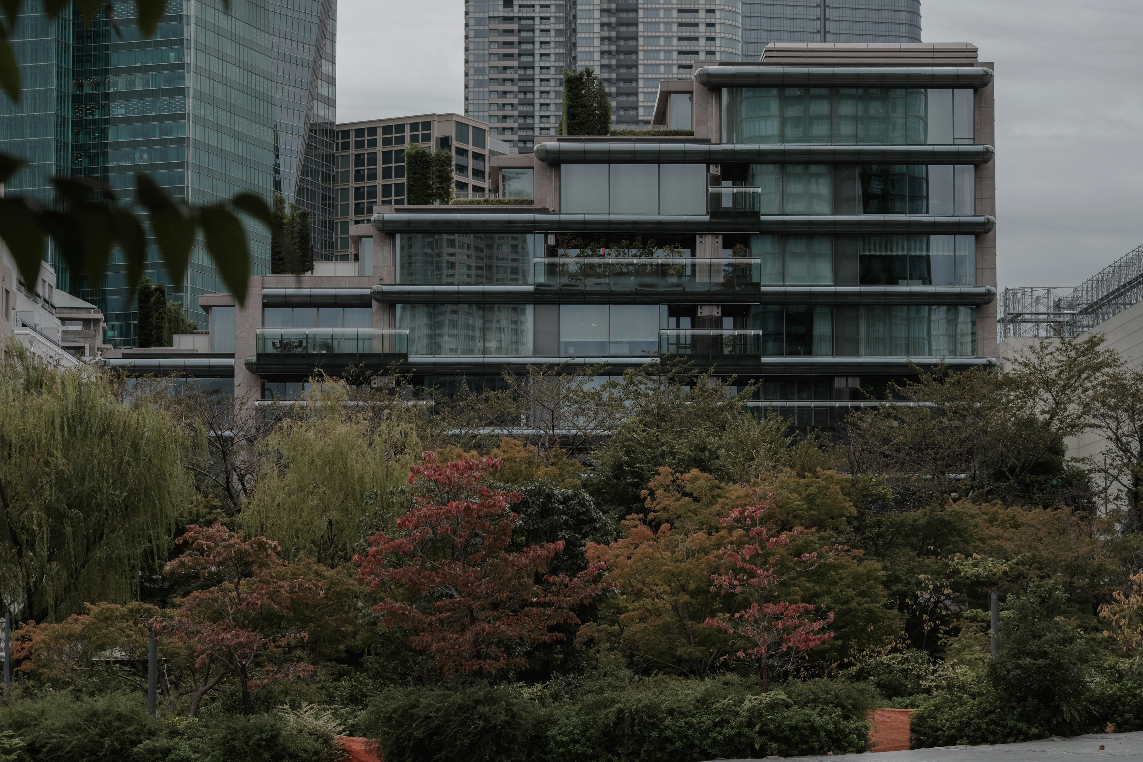 Moderne Glasgebäude umgeben von bunten Bäumen in einer Gartenlandschaft