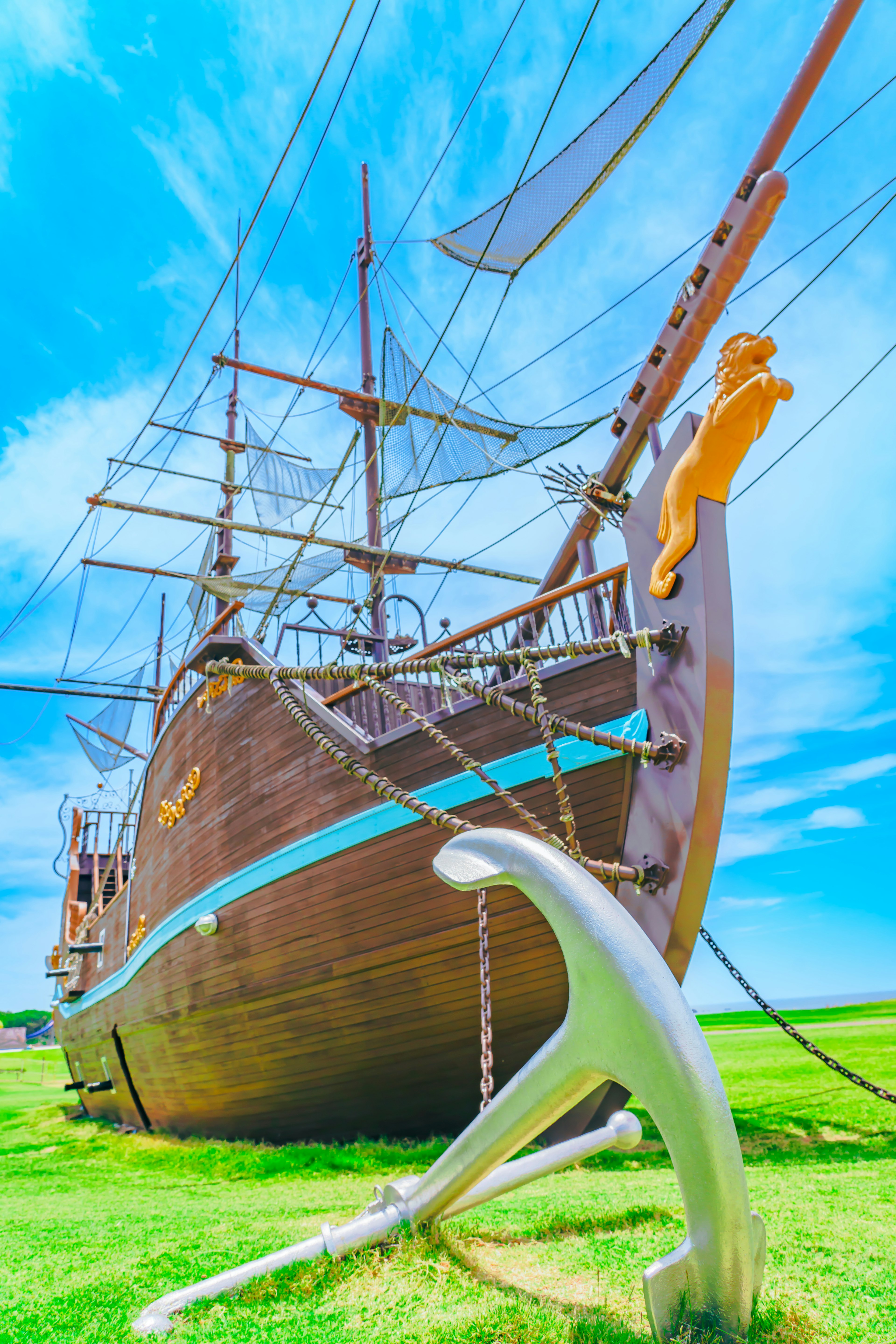 A beautiful wooden ship under a blue sky featuring striking blue lines and a large anchor