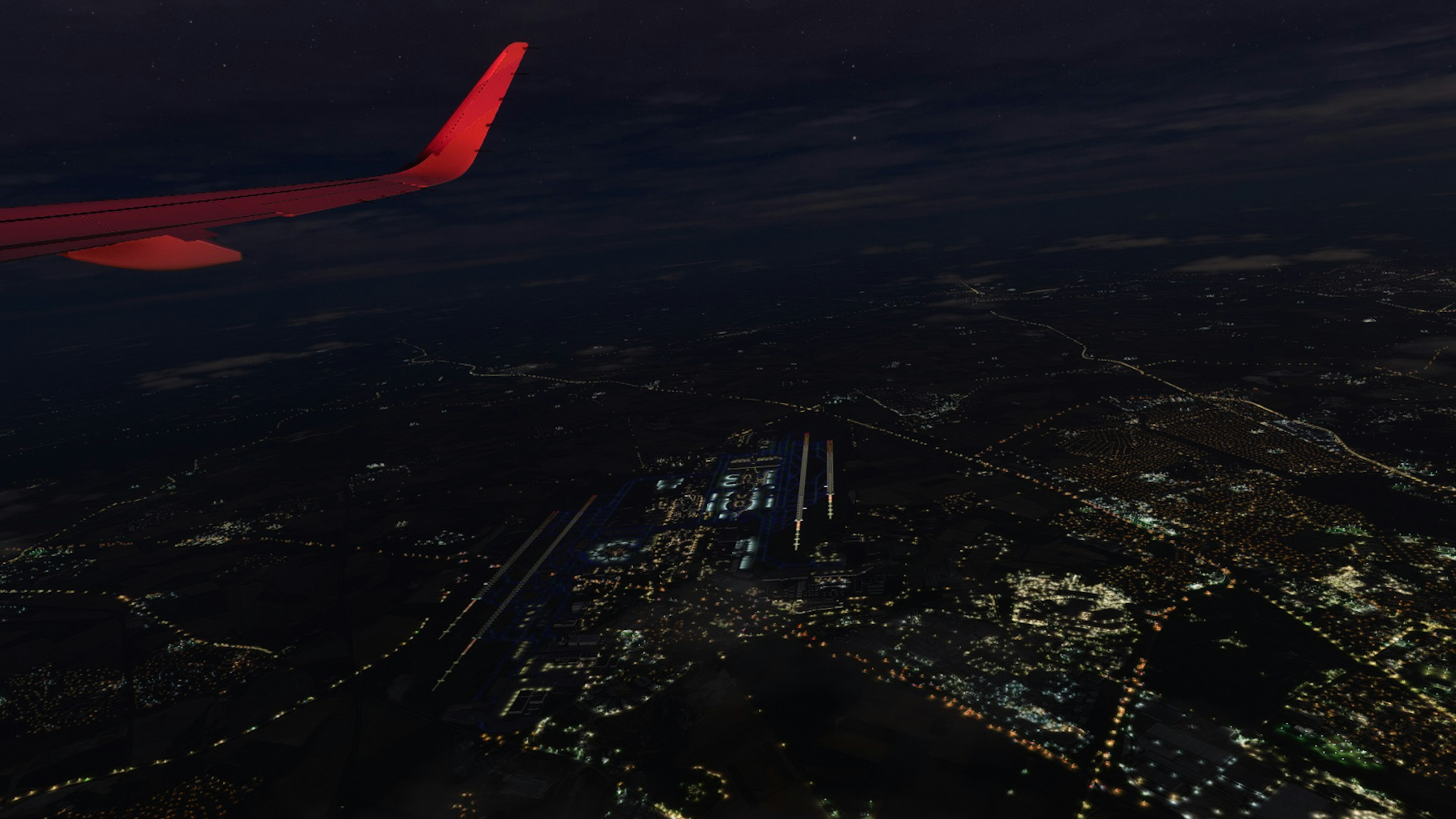 City lights viewed from above at night with airplane wing