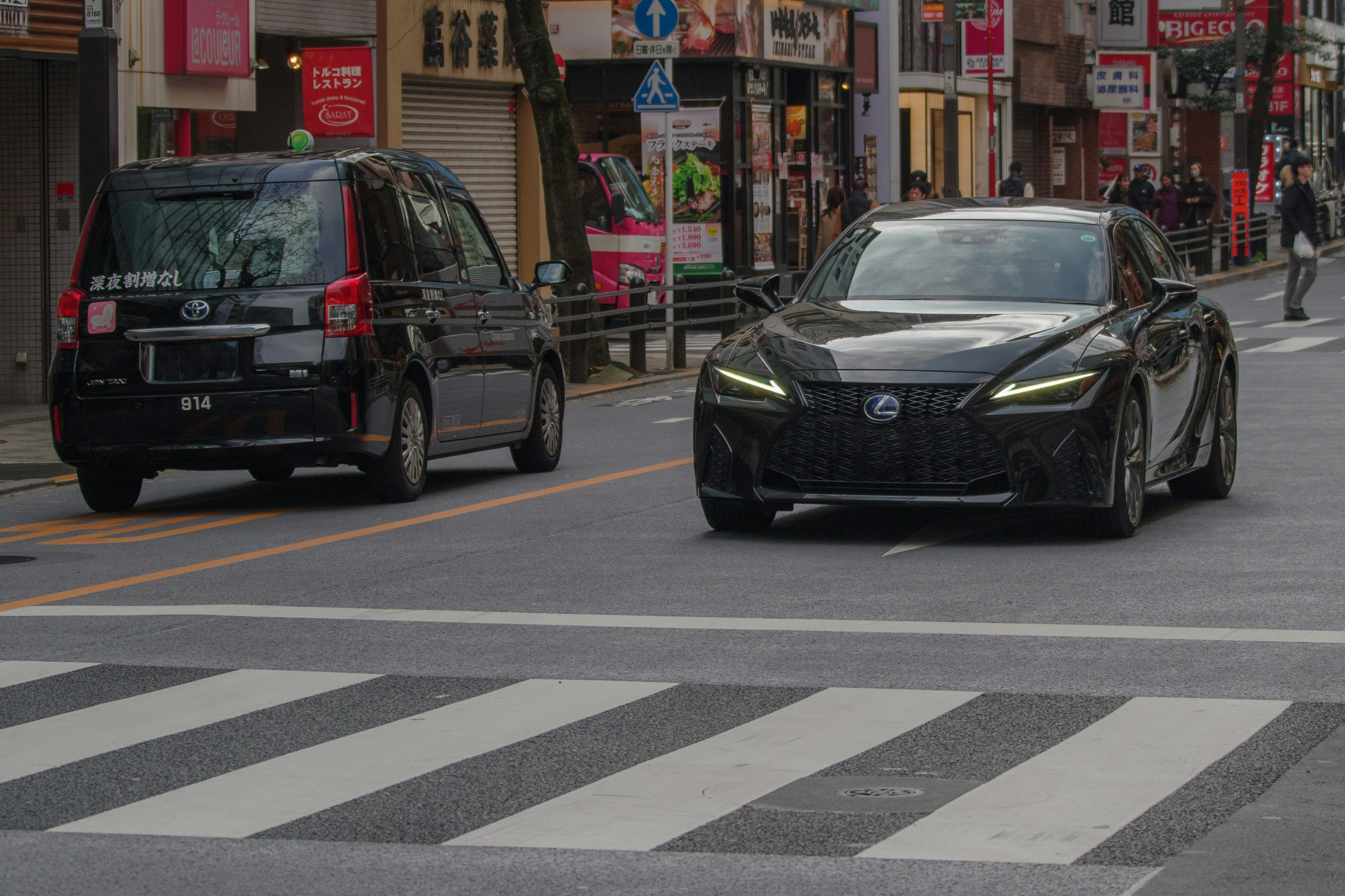 黑色豪華車在城市環境中通過人行道