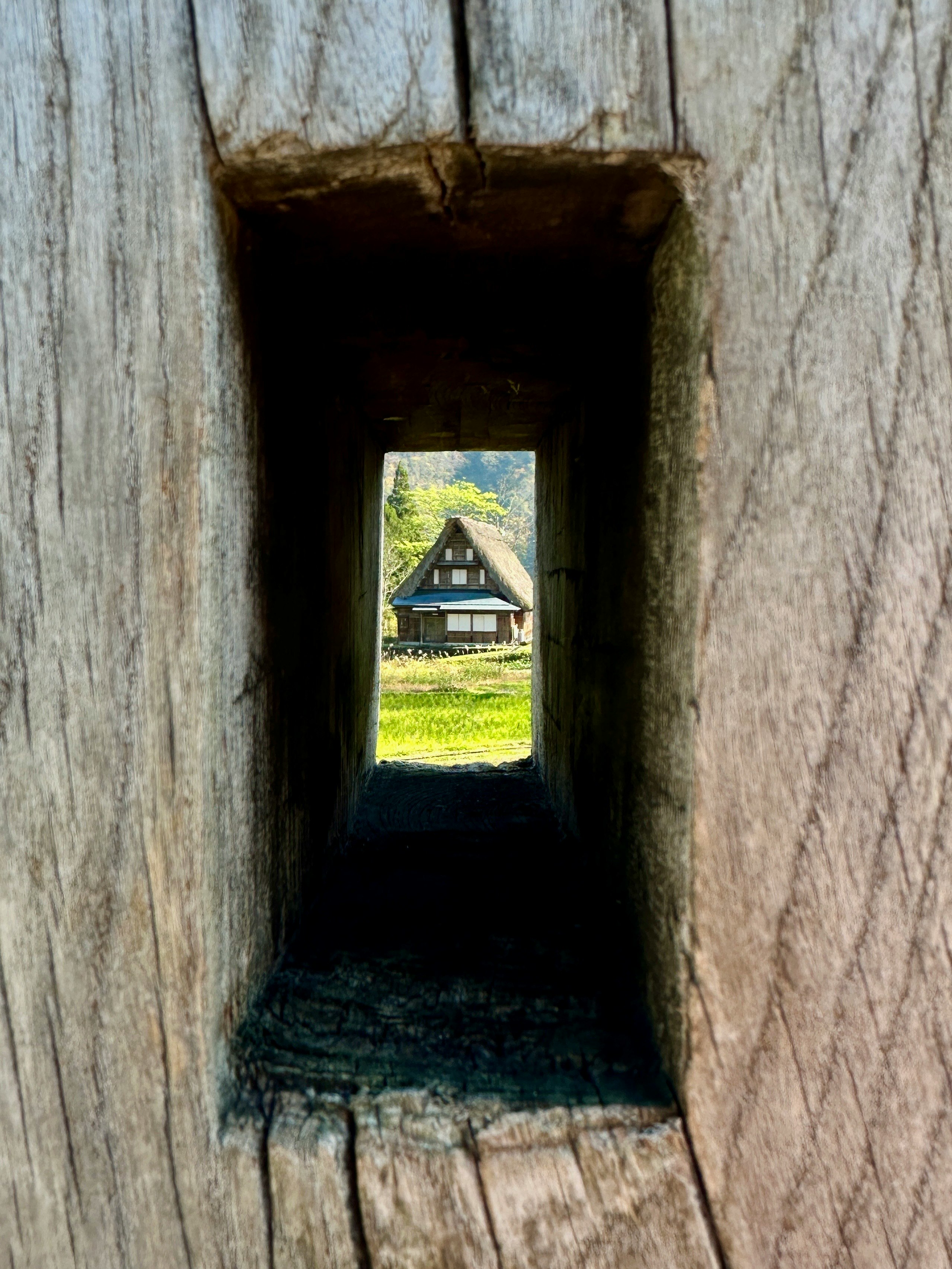 Vista di una casa tradizionale attraverso un'apertura in legno