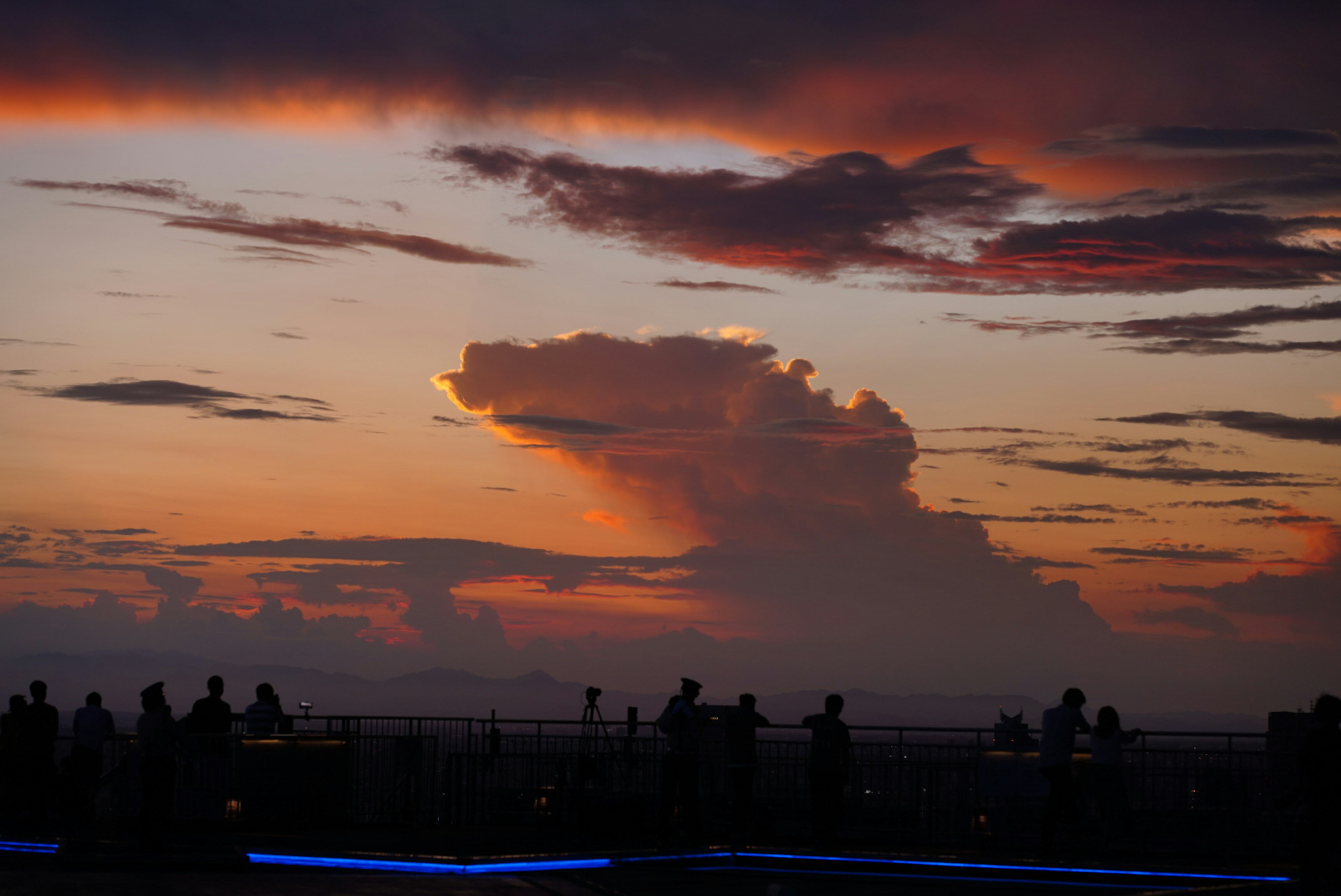 夕焼けの空に浮かぶ雲とシルエットの人々