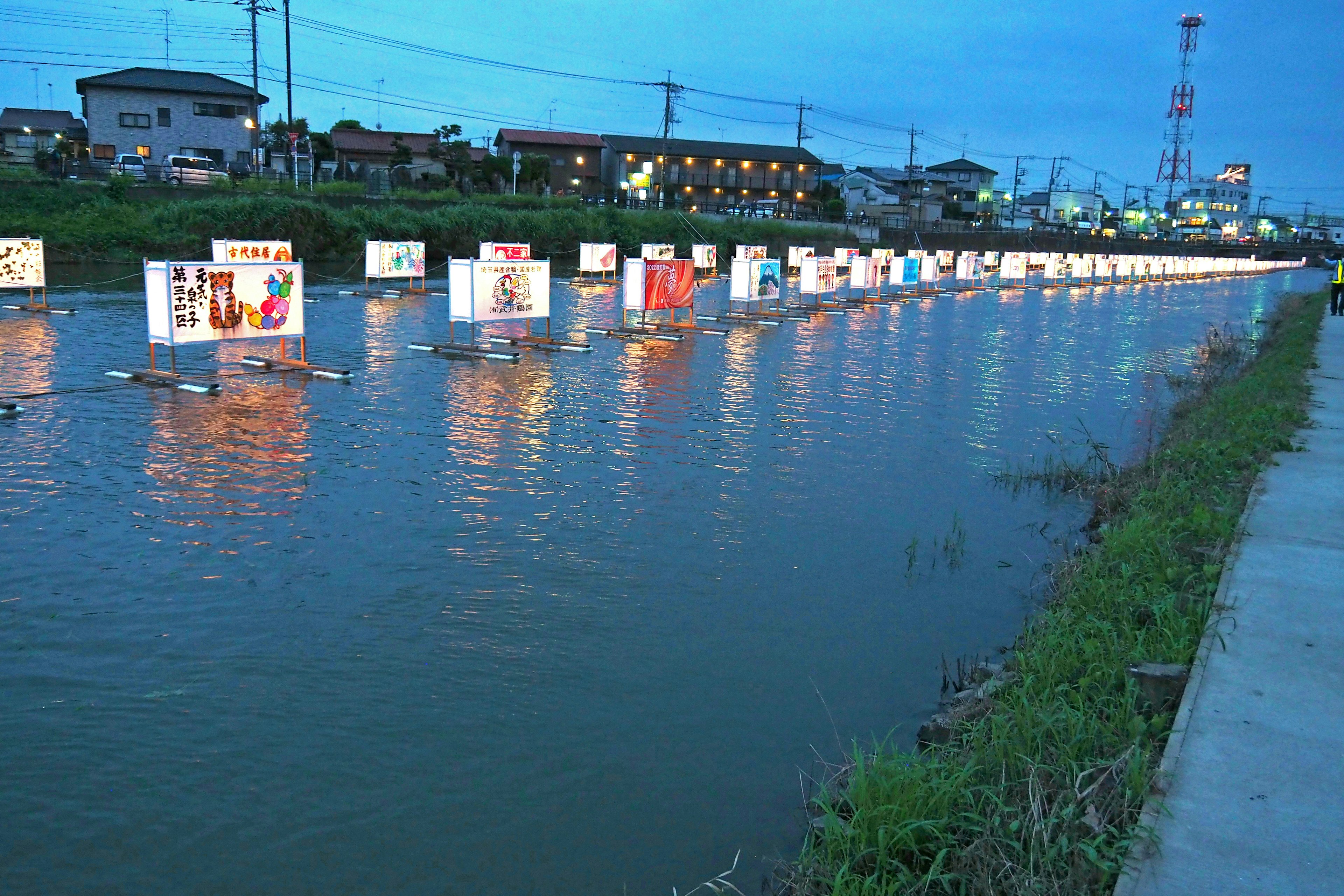 Escena de río con paneles publicitarios iluminados flotando en el agua