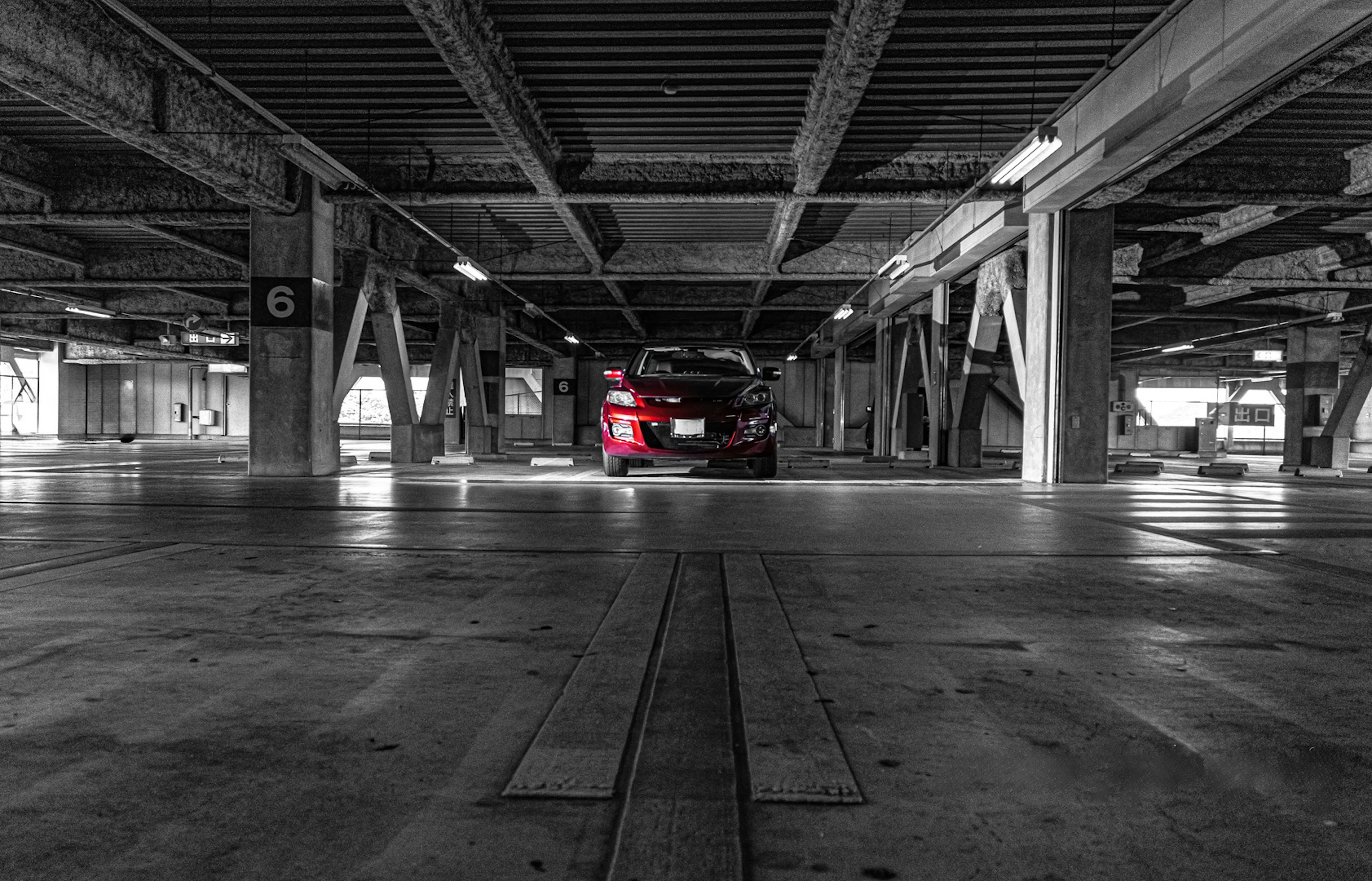 Un garaje con un coche rojo en un entorno en blanco y negro