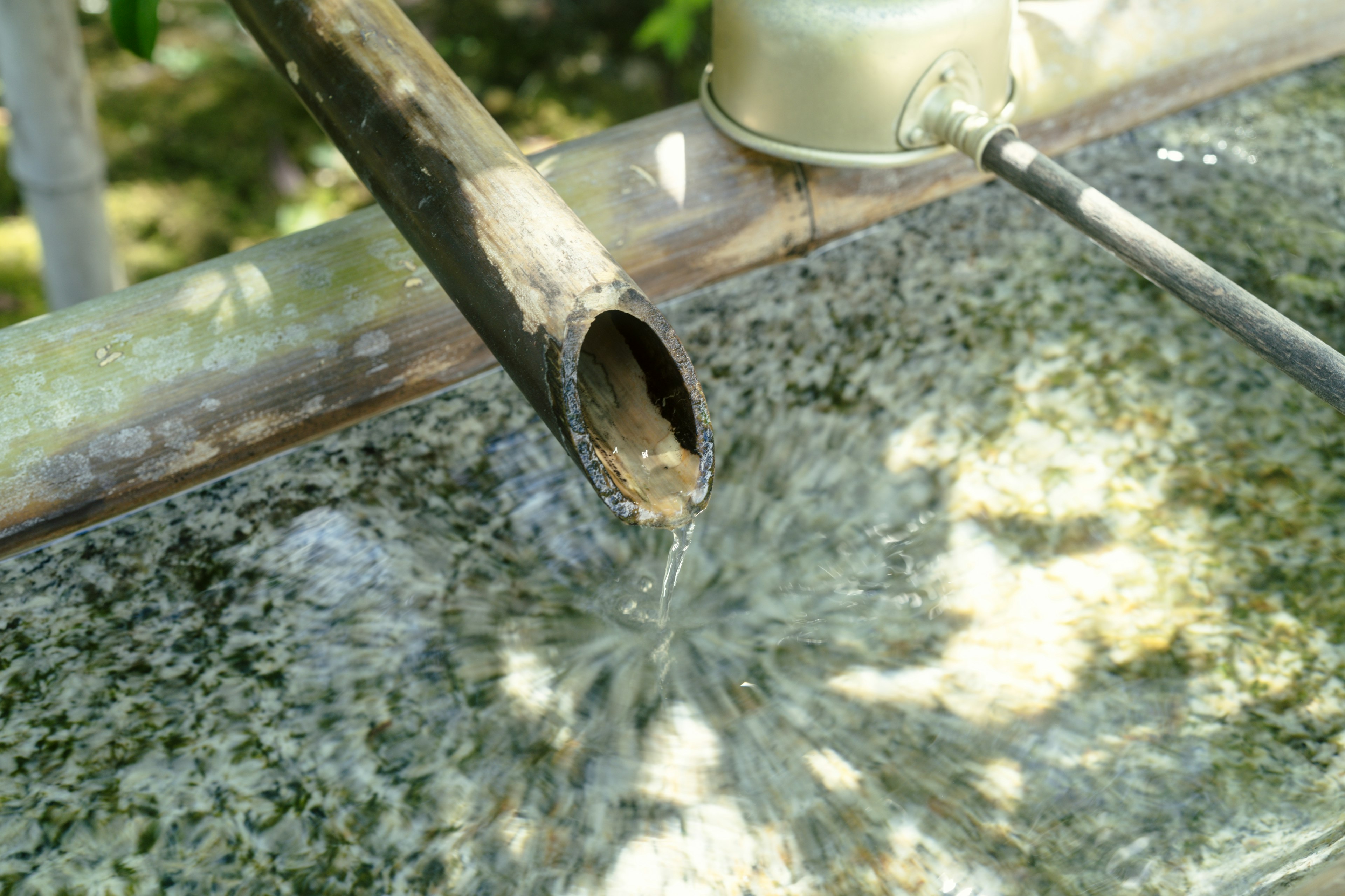 Primo piano di un tubo di metallo con acqua che scorre sfondo verde e acqua trasparente