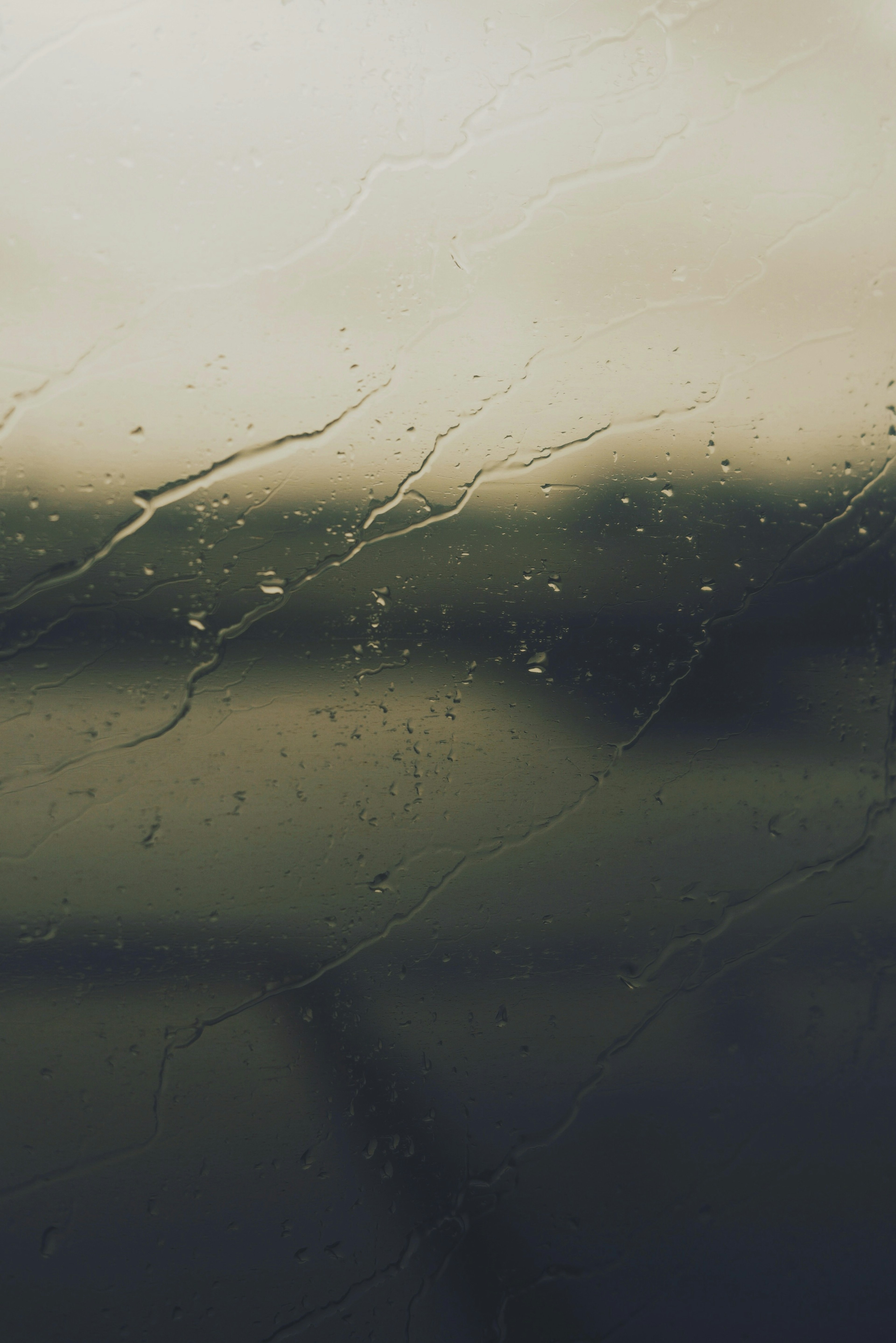 Verschwommene Landschaft durch ein Fenster mit Regentropfen