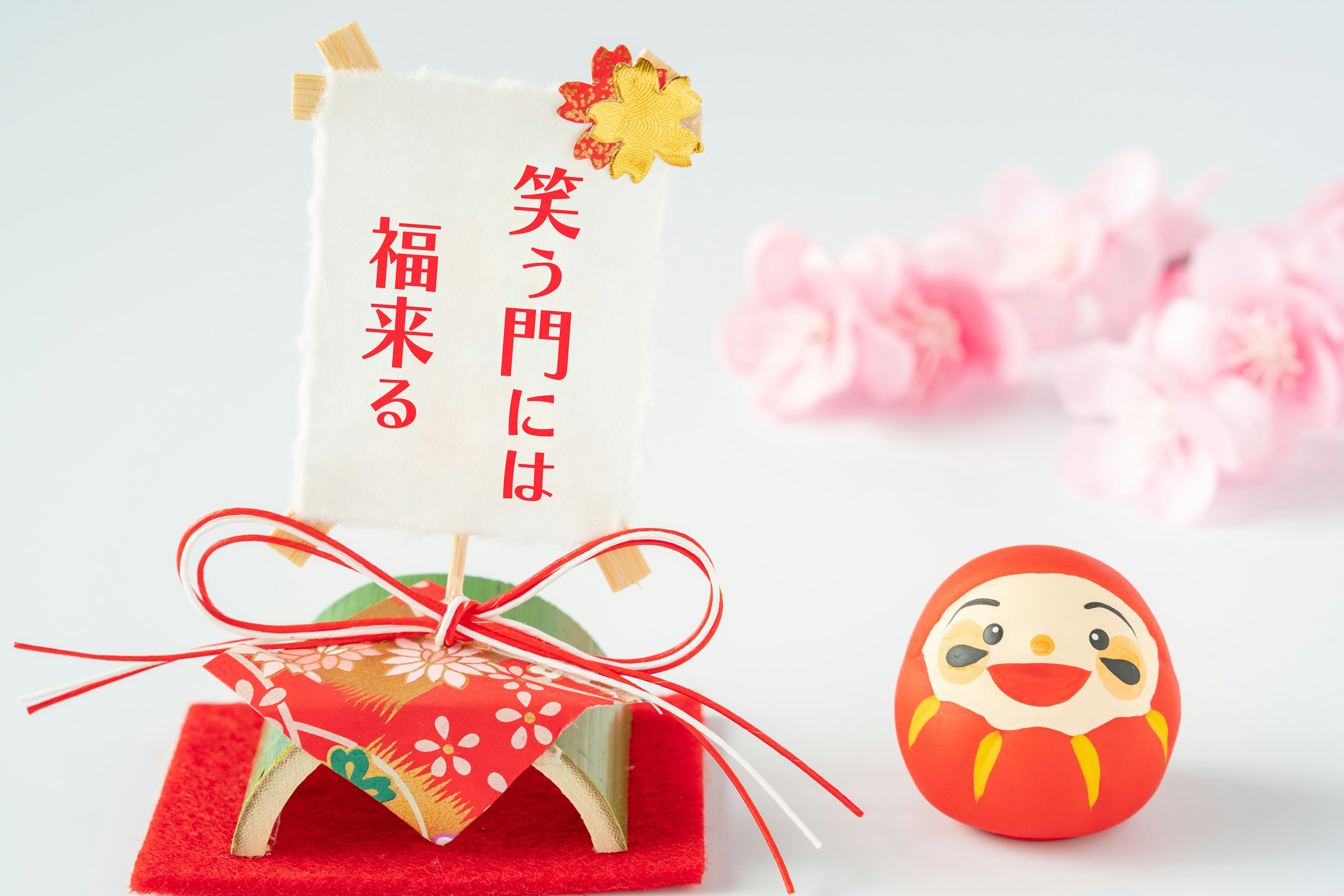 Decoración japonesa tradicional con un Daruma rojo y elementos florales